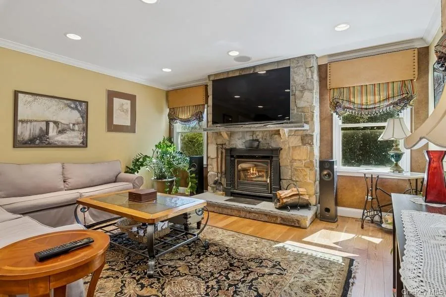 Warm den featuring soft yellow walls, recessed ceiling lighting, and a wood-burning fireplace with stone surround Warm den featuring soft yellow walls, recessed ceiling lighting, and a wood-burning fireplace with stone surround