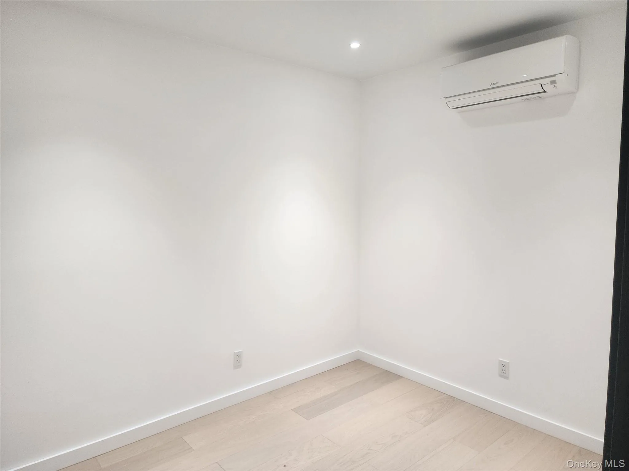 Second room. Recessed lighting, light wood-finish flooring, white walls, and a wall-mounted air conditioning unit Second room. Recessed lighting, light wood-finish flooring, white walls, and a wall-mounted air conditioning unit