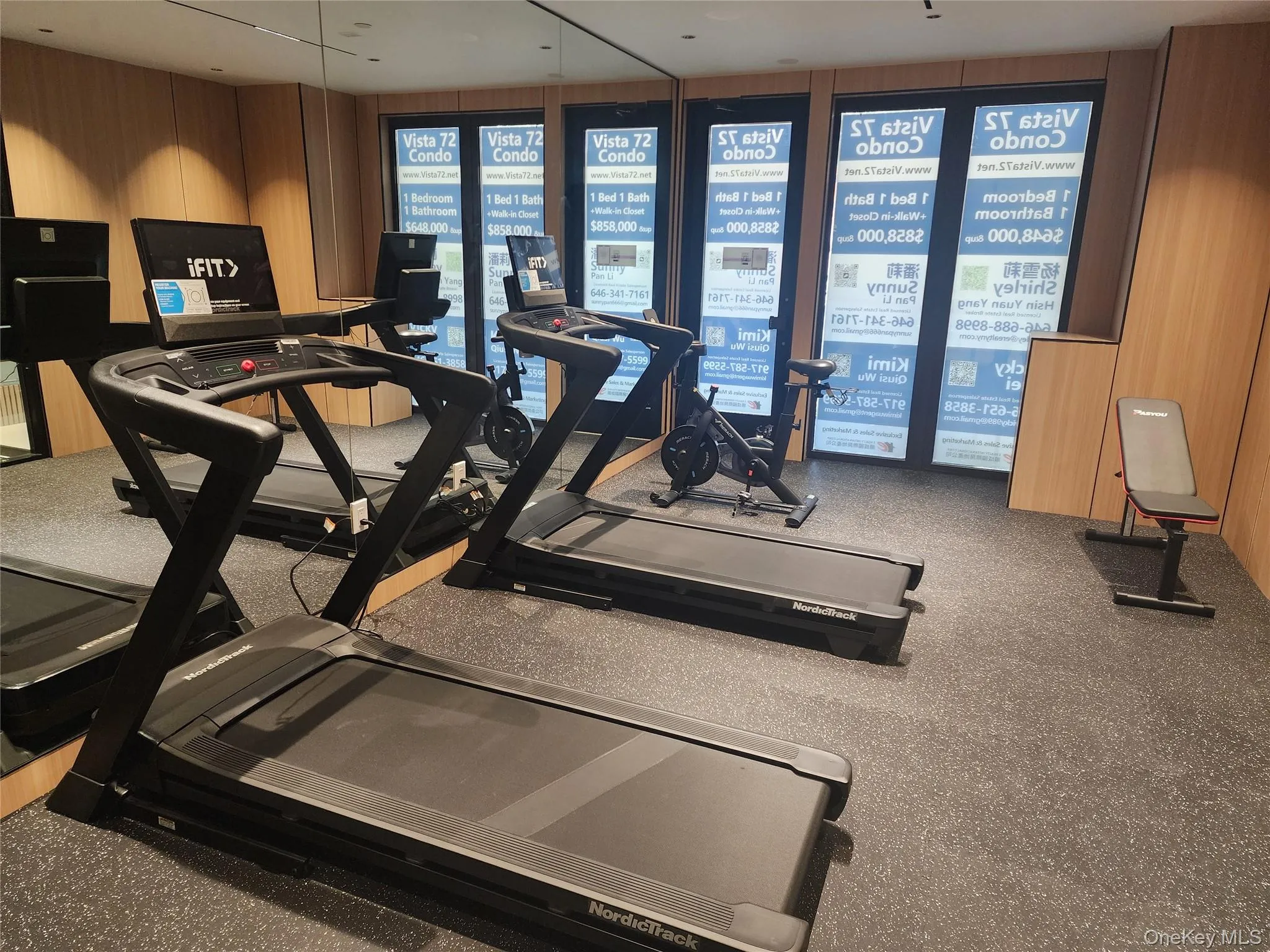 Fitness area featuring two treadmills, an exercise bike, a weight bench, and a rubberized flooring surface Fitness area featuring two treadmills, an exercise bike, a weight bench, and a rubberized flooring surface