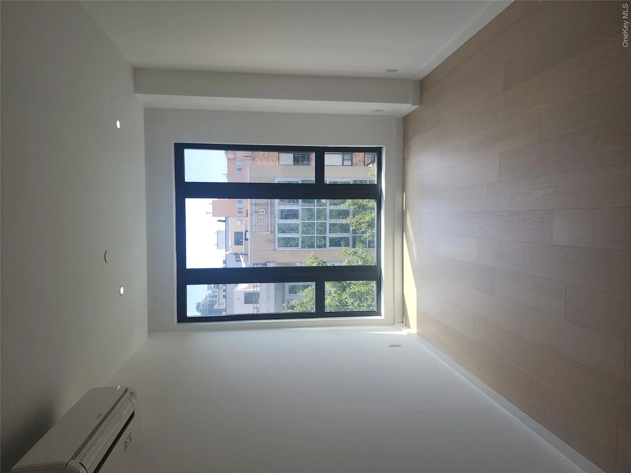 Light wood-finish flooring, recessed ceiling lighting, split air conditioning unit, and a large multi-pane window Light wood-finish flooring, recessed ceiling lighting, split air conditioning unit, and a large multi-pane window