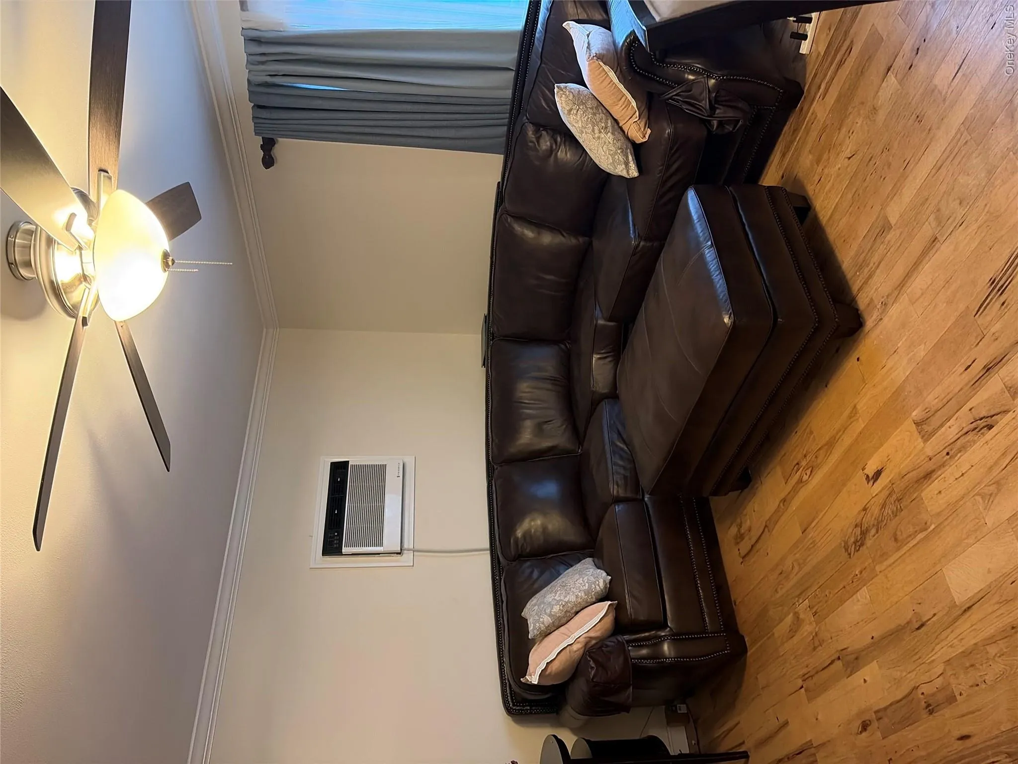 Wood-finish flooring with crown molding, a ceiling fan with integrated lighting, and a wall-mounted air conditioning unit Wood-finish flooring with crown molding, a ceiling fan with integrated lighting, and a wall-mounted air conditioning unit
