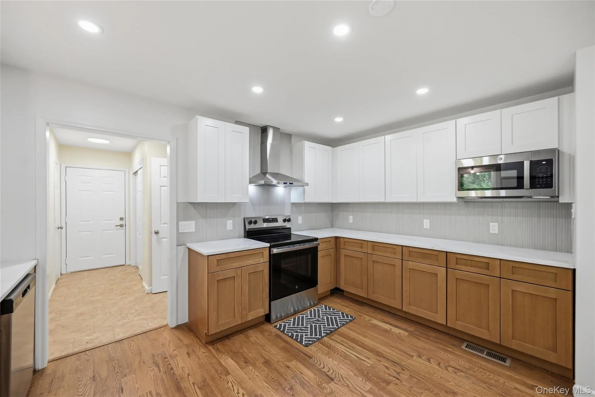 Wood-finish flooring, white upper cabinetry, natural wood lower cabinetry, stainless steel appliances, and recessed lighting Wood-finish flooring, white upper cabinetry, natural wood lower cabinetry, stainless steel appliances, and recessed lighting