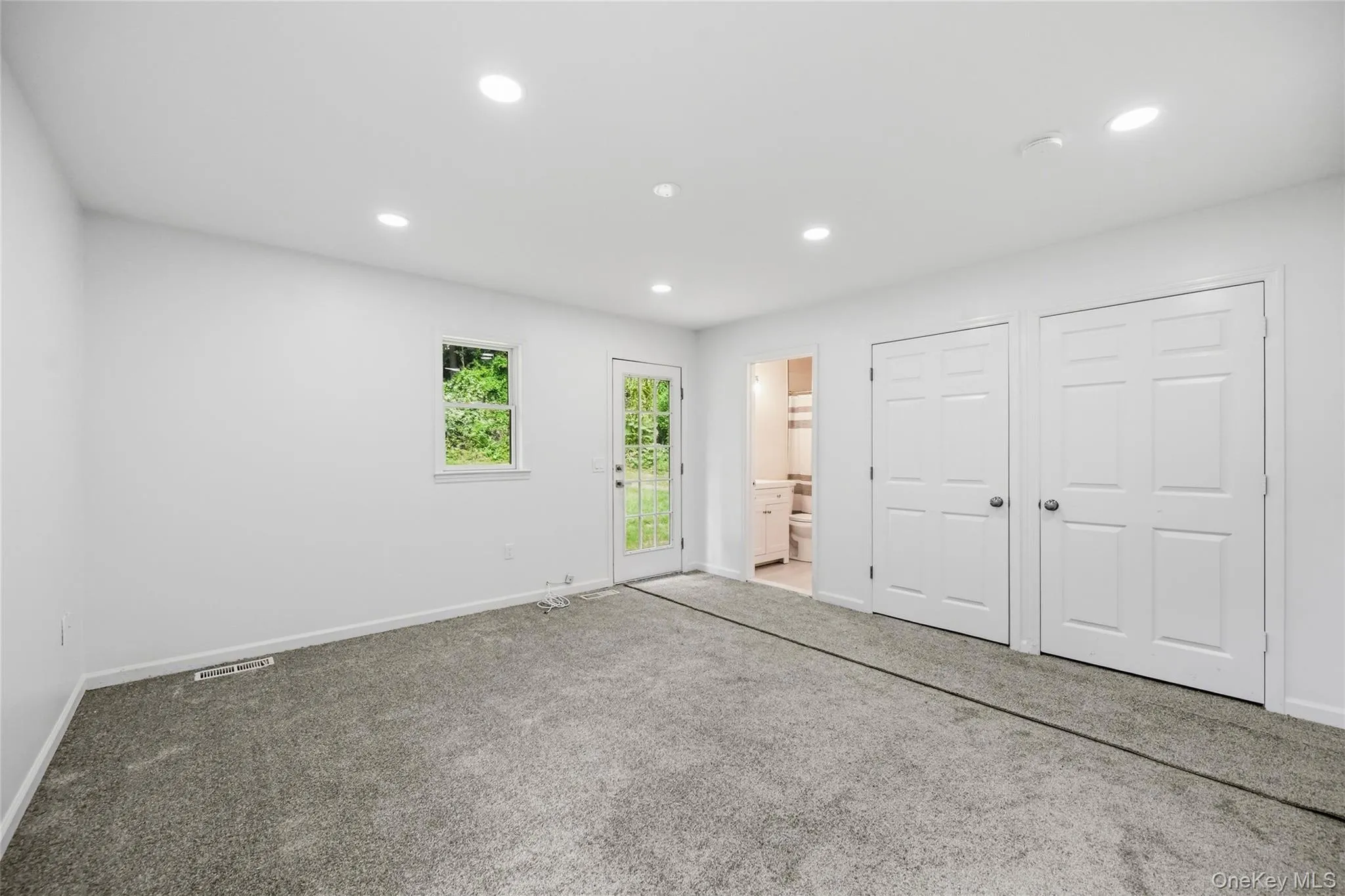 Recessed lighting, carpet flooring, a window, and double bi-fold closet doors Recessed lighting, carpet flooring, a window, and double bi-fold closet doors