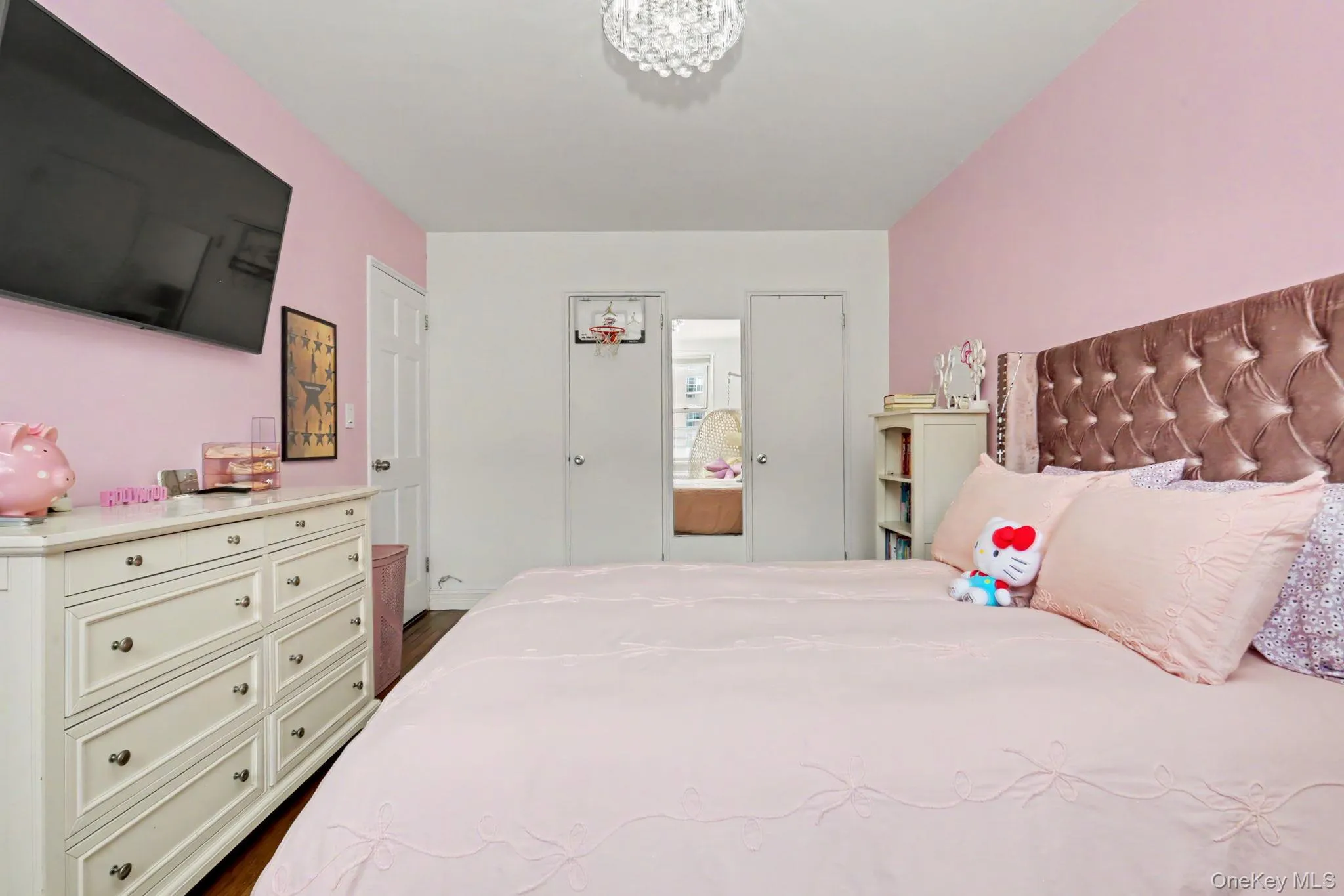 Built-in ceiling light fixture, white paneled doors, hardwood flooring, and a decorative headboard Built-in ceiling light fixture, white paneled doors, hardwood flooring, and a decorative headboard