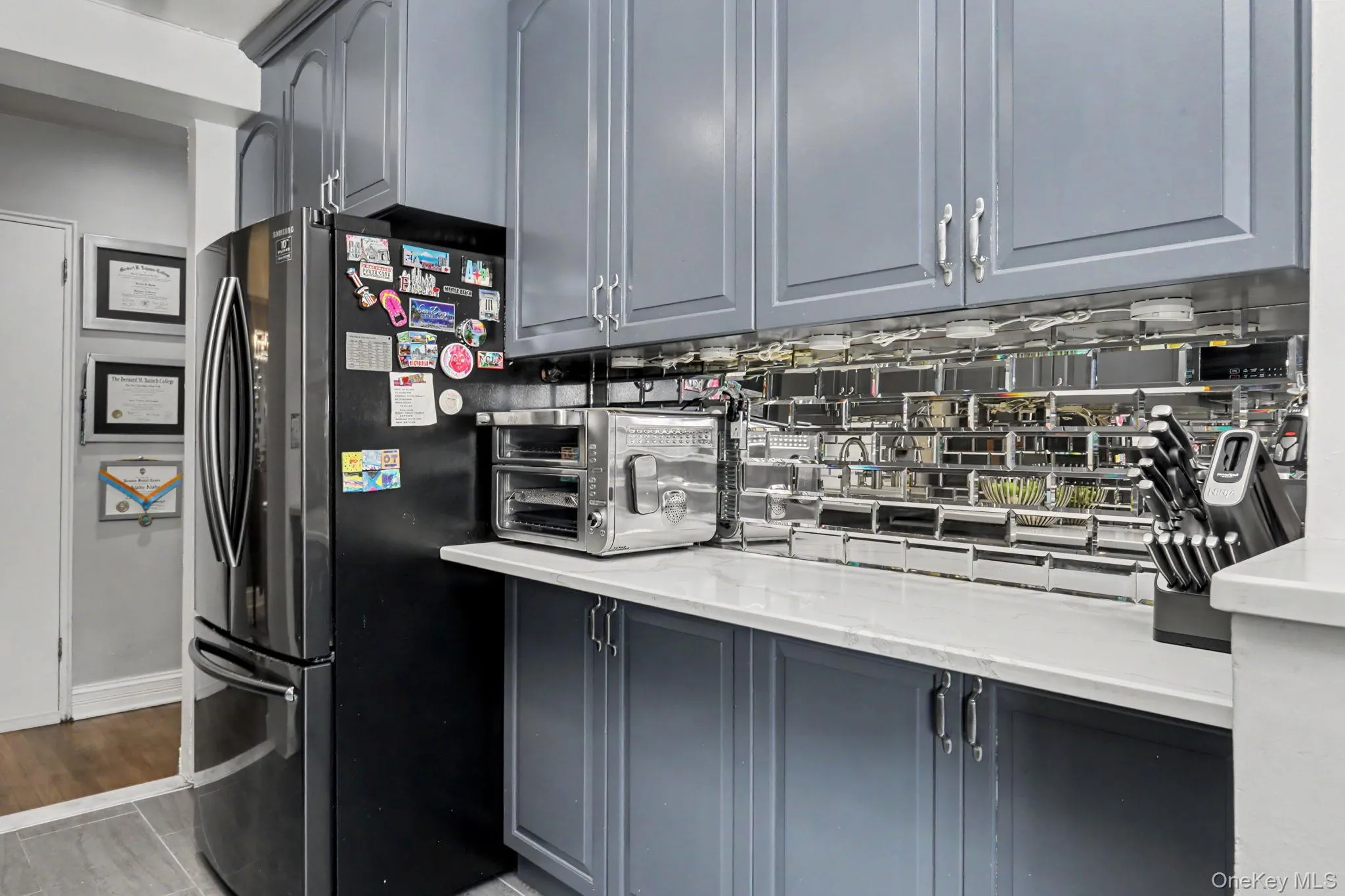 Gray shaker-style cabinetry, white countertops, and a reflective tile backsplash Gray shaker-style cabinetry, white countertops, and a reflective tile backsplash