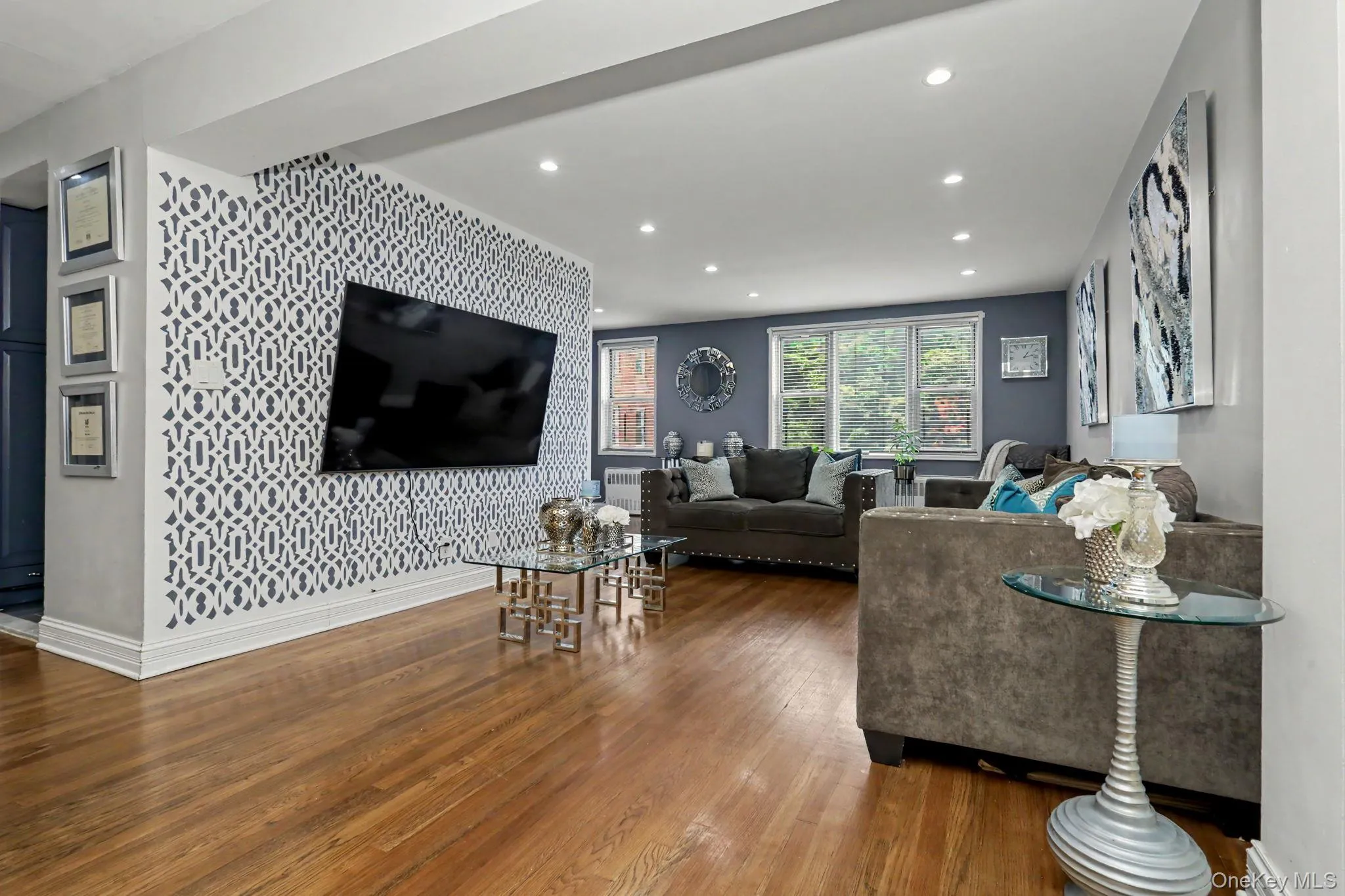 Wood-finish flooring, recessed ceiling lighting, a decorative accent wall, and a large window with exterior scenery Wood-finish flooring, recessed ceiling lighting, a decorative accent wall, and a large window with exterior scenery