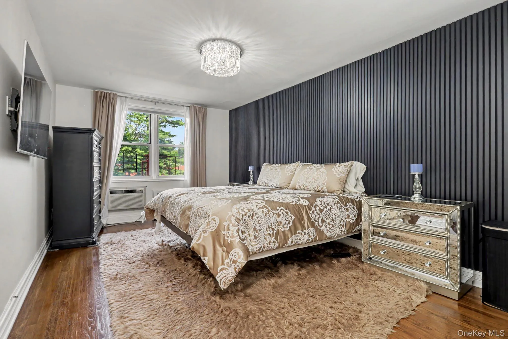 Feature wall with vertical paneling, recessed window, hardwood-finish flooring, and a crystal flush-mount light fixture Feature wall with vertical paneling, recessed window, hardwood-finish flooring, and a crystal flush-mount light fixture