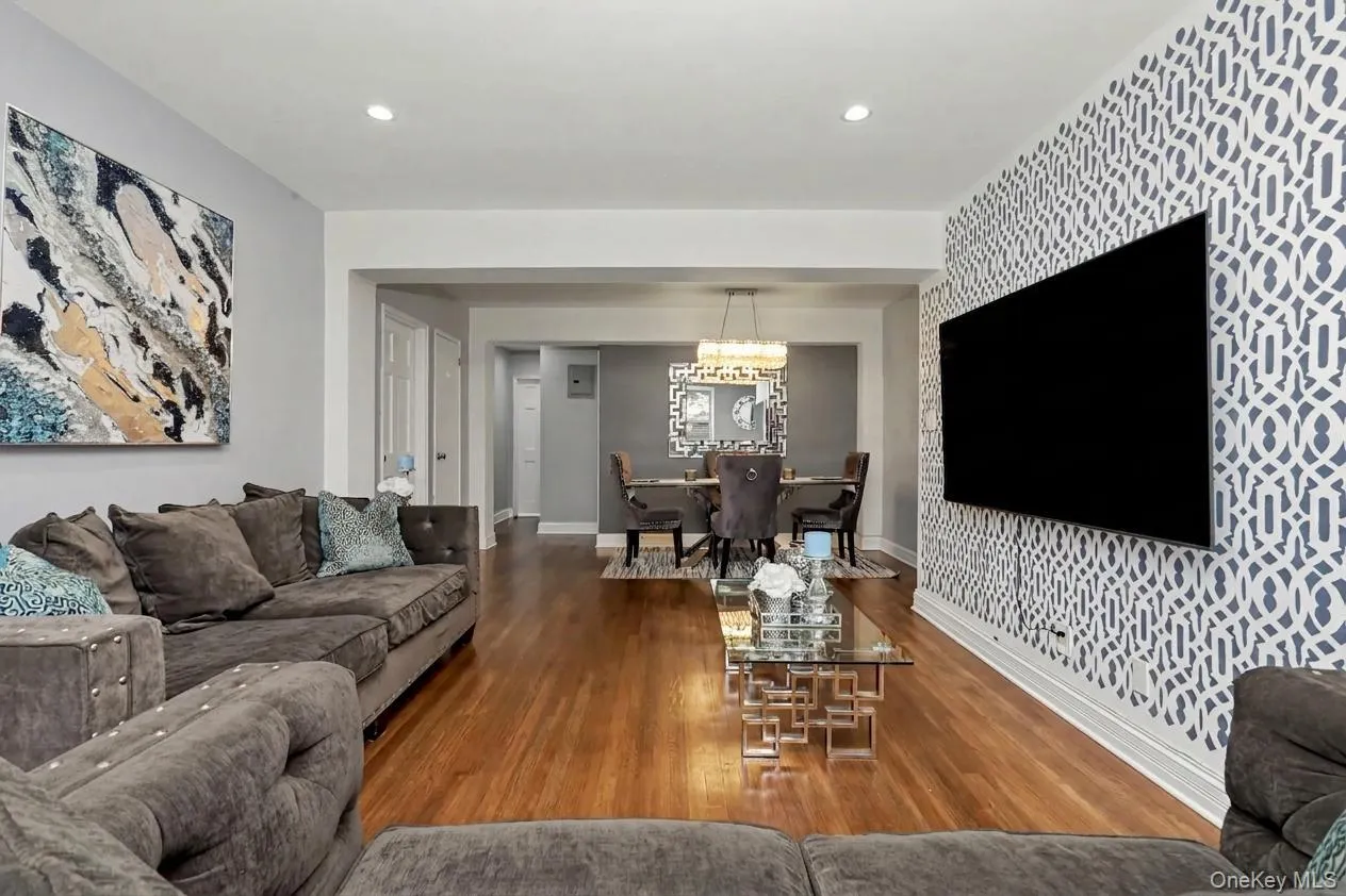 Wood-finish flooring throughout, recessed ceiling lighting, and a patterned accent wall Wood-finish flooring throughout, recessed ceiling lighting, and a patterned accent wall