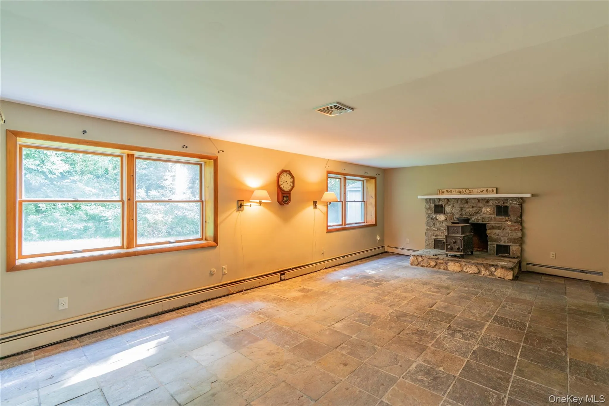 Family Room with stone-clad fireplace with hearth, wood-framed windows, and wall-mounted lighting Family Room with stone-clad fireplace with hearth, wood-framed windows, and wall-mounted lighting