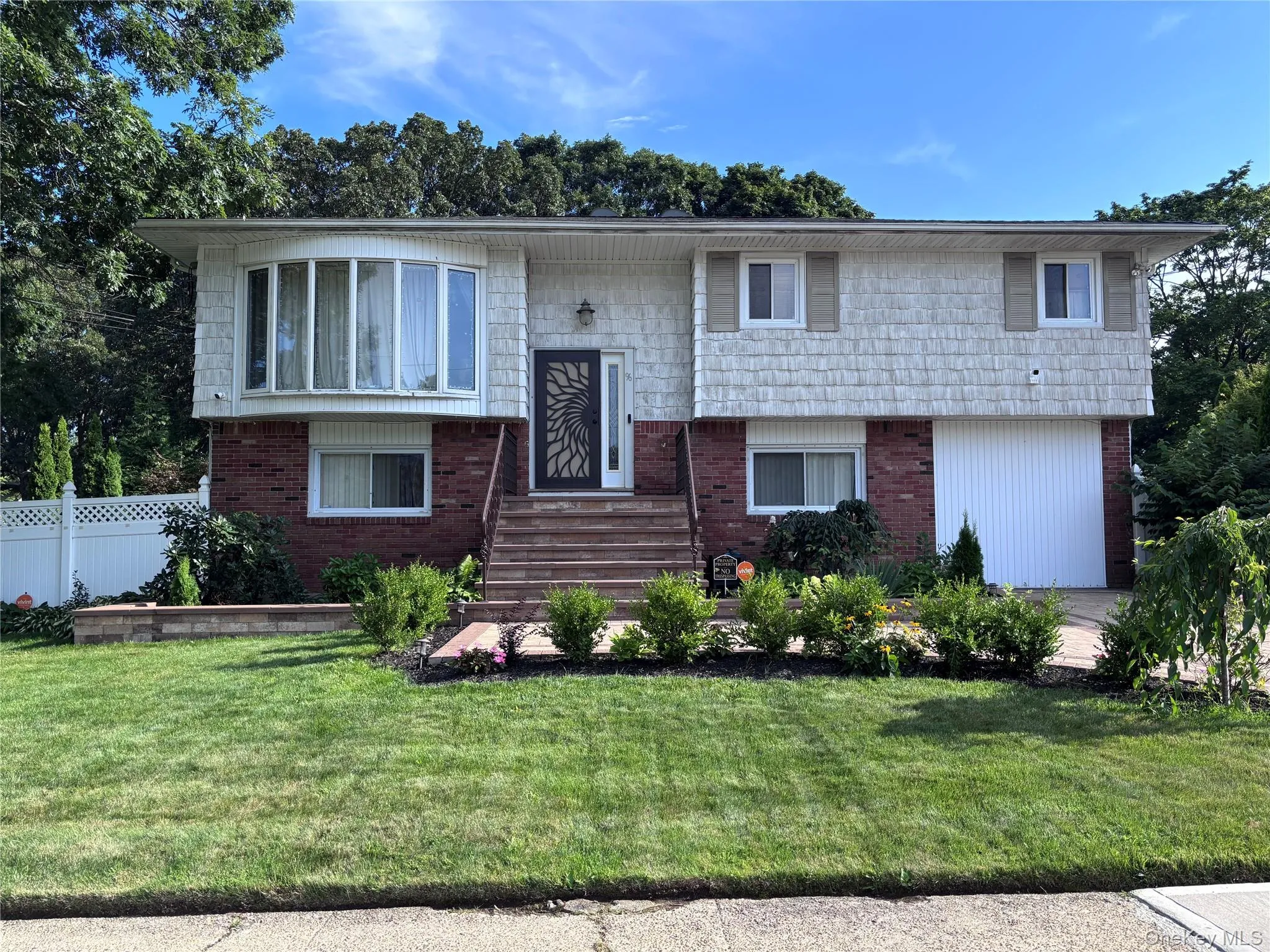 Split-level residence featuring brick and shake siding, a bay window, and exterior steps with railing Split-level residence featuring brick and shake siding, a bay window, and exterior steps with railing