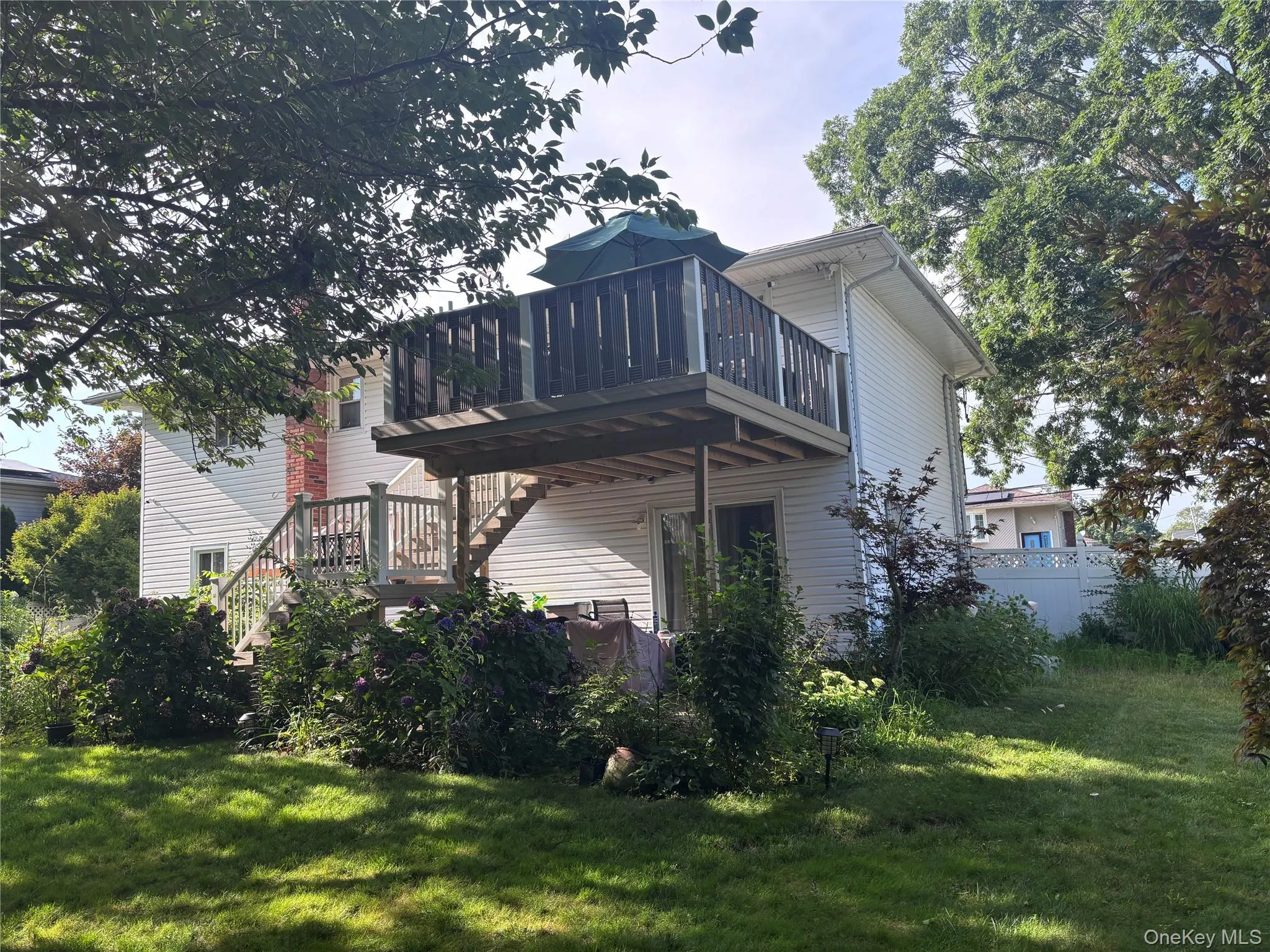 Two-story deck with wood railing, leading to a ground-level patio Two-story deck with wood railing, leading to a ground-level patio