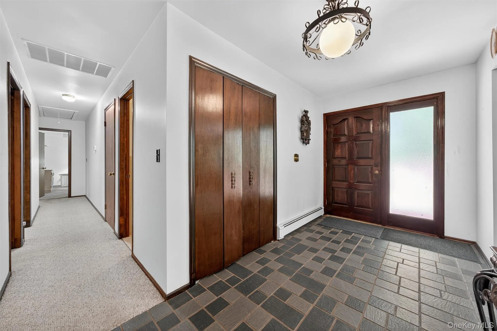 Foyer entrance with a baseboard radiator and dark colored carpet Foyer entrance with a baseboard radiator and dark colored carpet