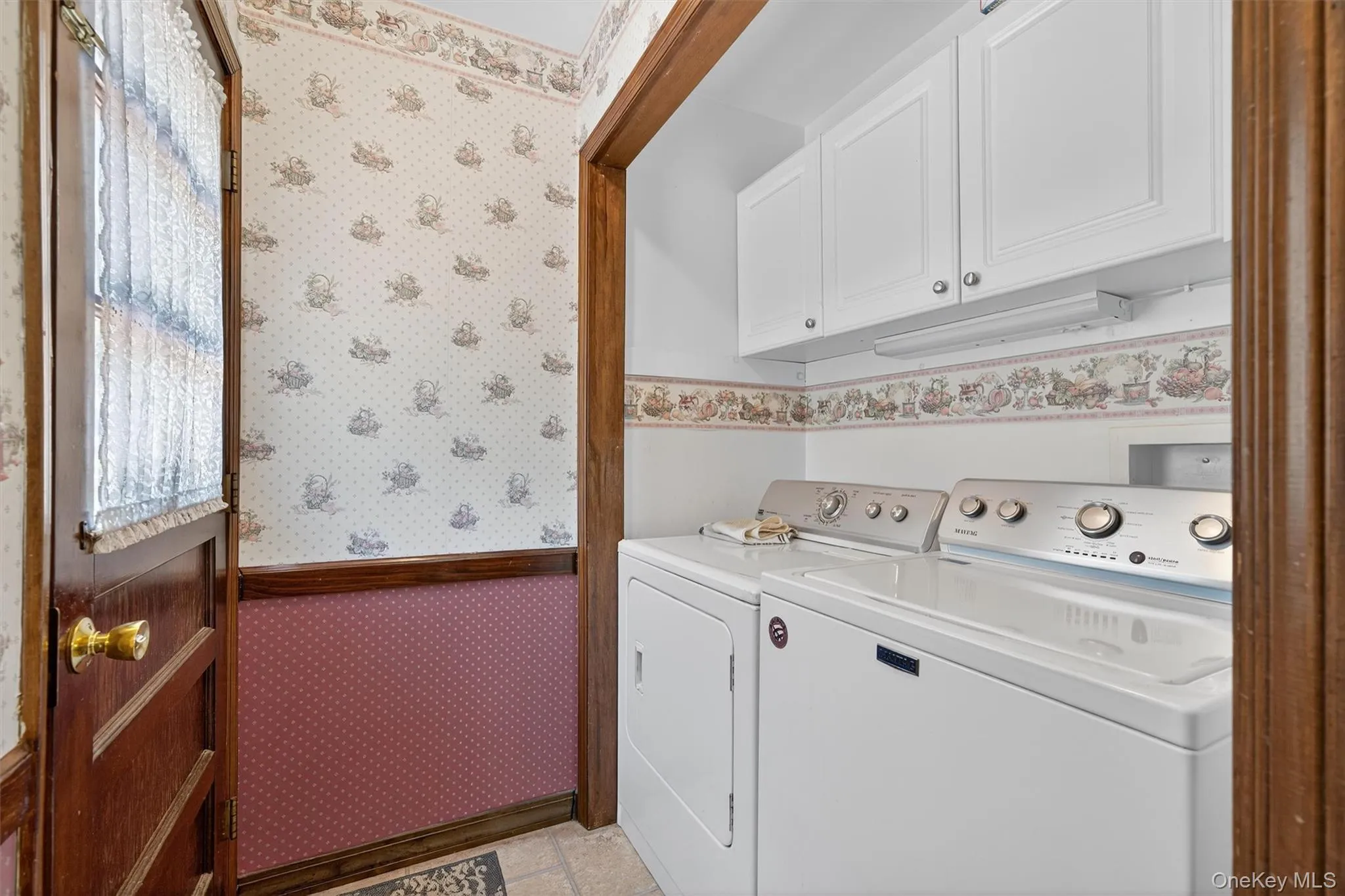 Laundry room with wallpapered walls, washing machine and clothes dryer, and cabinet space Laundry room with wallpapered walls, washing machine and clothes dryer, and cabinet space