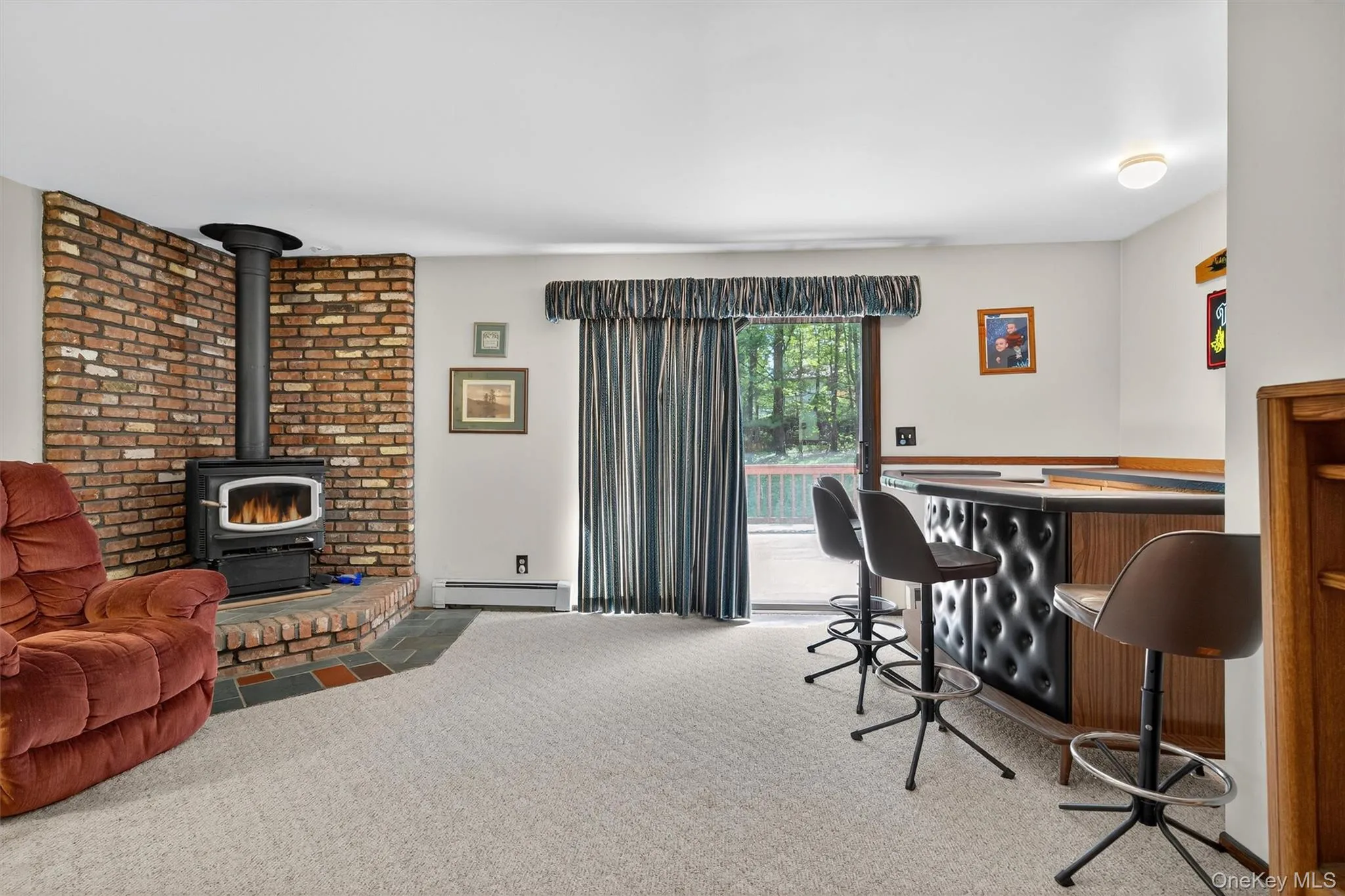 Office area with a baseboard heating unit, a dry bar, a wood stove, and carpet Office area with a baseboard heating unit, a dry bar, a wood stove, and carpet