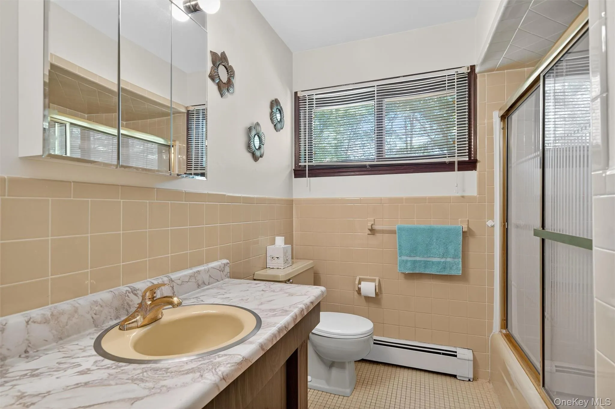 Full bathroom featuring baseboard heating, vanity, tile patterned flooring, tile walls, and wainscoting Full bathroom featuring baseboard heating, vanity, tile patterned flooring, tile walls, and wainscoting
