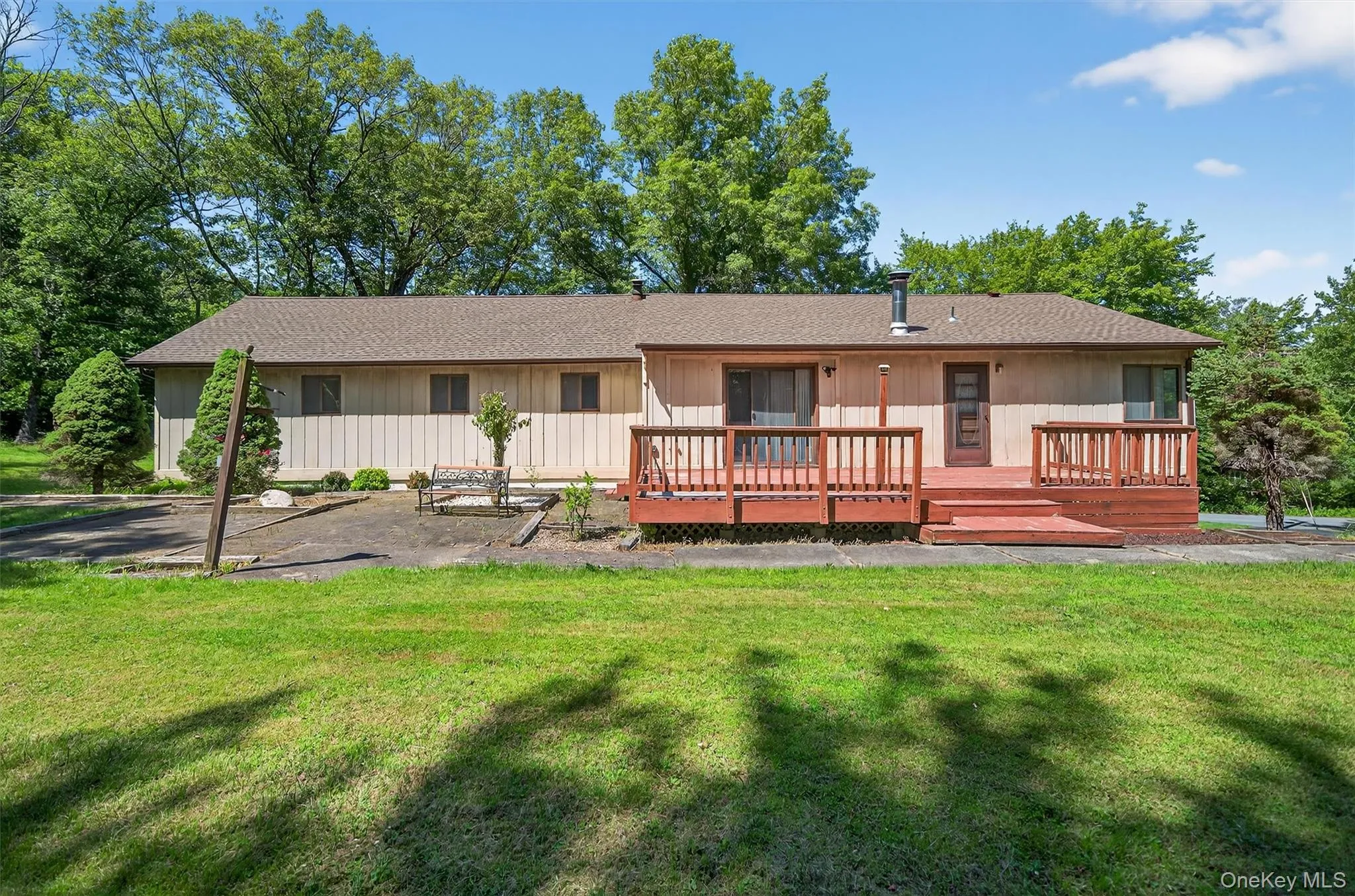 Rear view of house with a yard, a wooden deck, and roof with shingles Rear view of house with a yard, a wooden deck, and roof with shingles