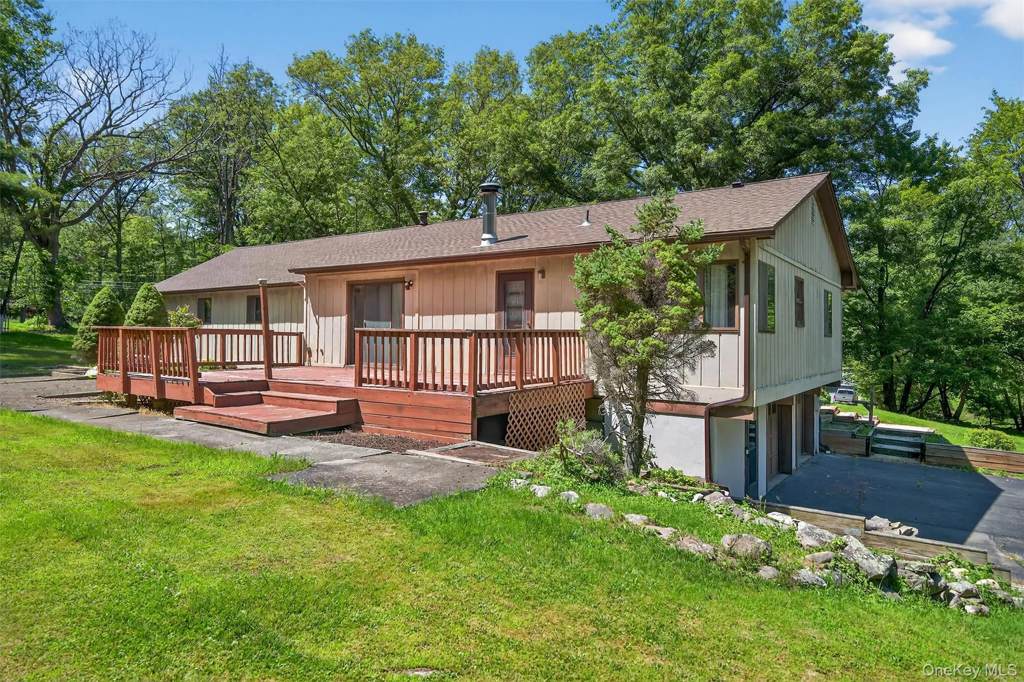 Back of property with a wooden deck, a yard, a garage, and roof with shingles Back of property with a wooden deck, a yard, a garage, and roof with shingles