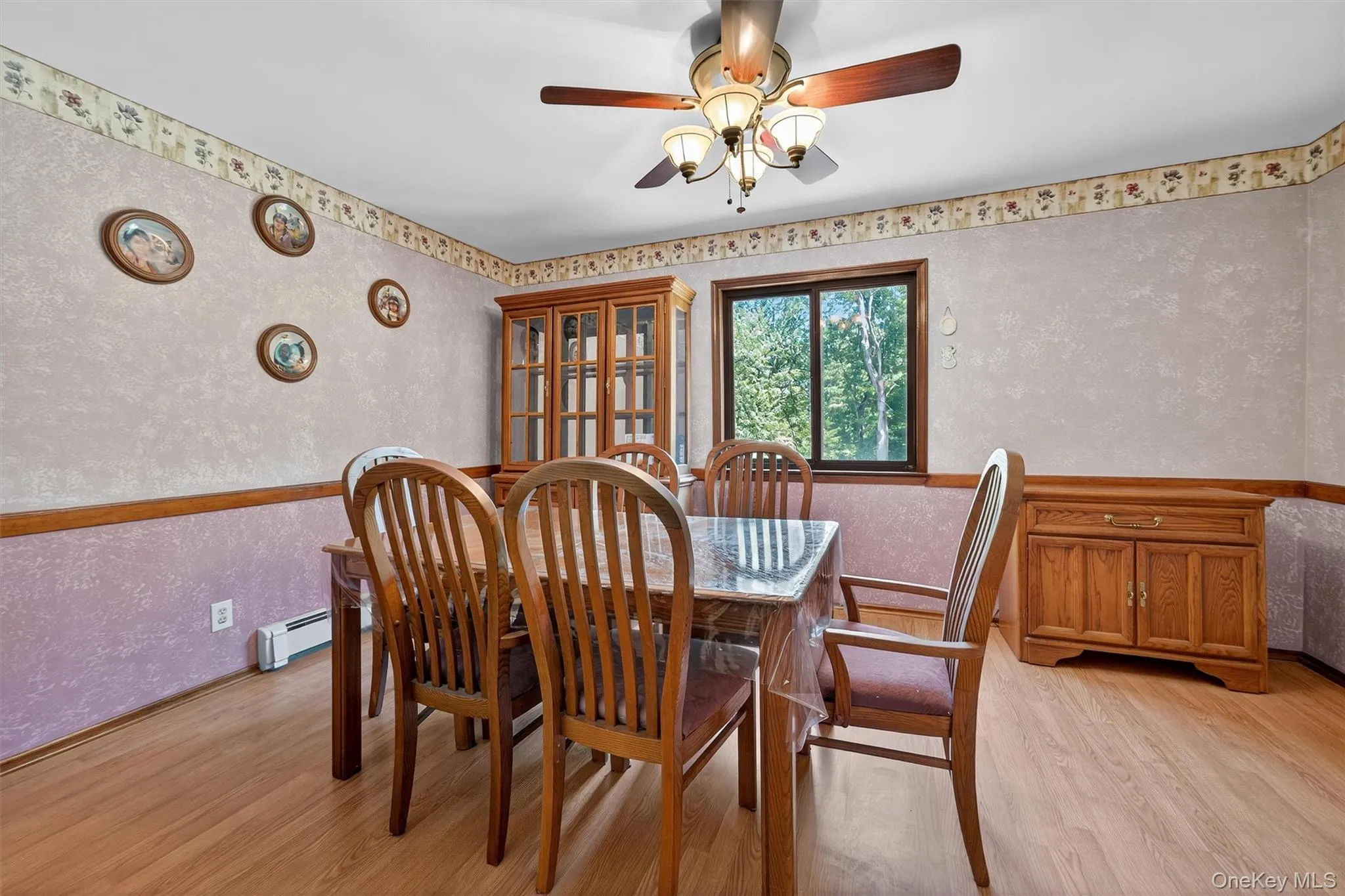 Dining room featuring light wood finished floors, a ceiling fan, baseboard heating, a textured wall, and wallpapered walls Dining room featuring light wood finished floors, a ceiling fan, baseboard heating, a textured wall, and wallpapered walls