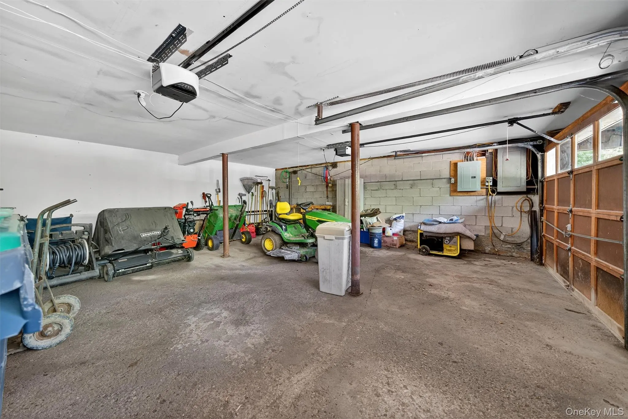 Garage with a garage door opener, electric panel, and concrete block wall Garage with a garage door opener, electric panel, and concrete block wall