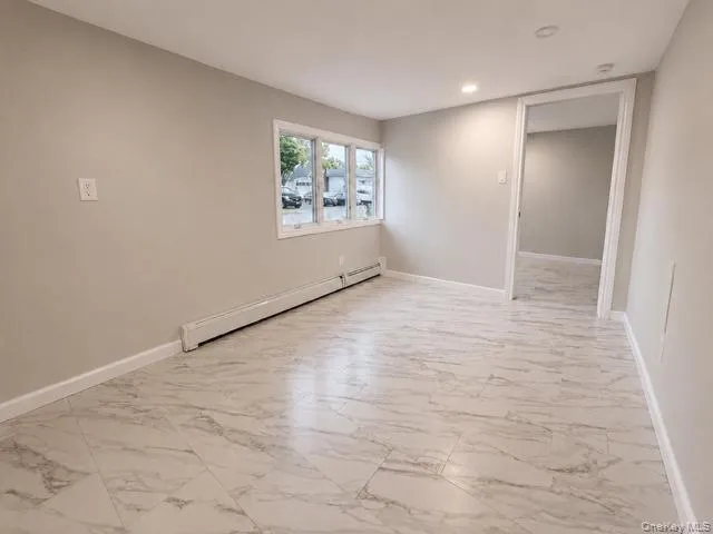 Bright, open living space featuring newly installed wood-finish flooring with marble-look detailing, recessed ceiling lighting, and large multi-pane windows providing natural light Bright, open living space featuring newly installed wood-finish flooring with marble-look detailing, recessed ceiling lighting, and large multi-pane windows providing natural light