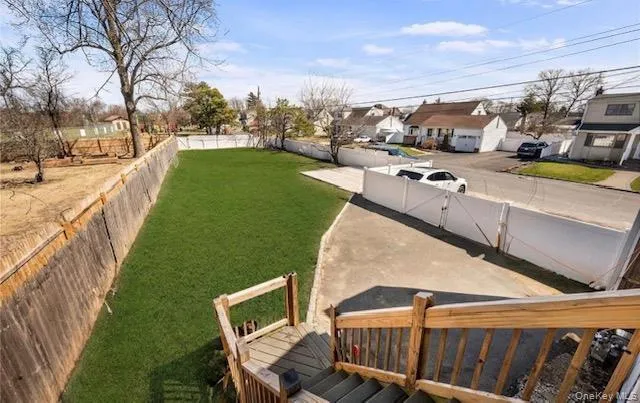 Expansive backyard featuring a professionally manicured lawn, wooden deck with railings, and mature landscaping Expansive backyard featuring a professionally manicured lawn, wooden deck with railings, and mature landscaping