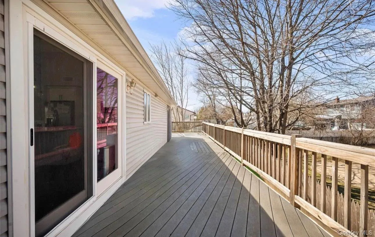 Spacious composite deck featuring composite decking with sturdy railings, sliding glass doors providing access to the interior, and mature tree backdrop offering natural screening and seasonal interest Spacious composite deck featuring composite decking with sturdy railings, sliding glass doors providing access to the interior, and mature tree backdrop offering natural screening and seasonal interest