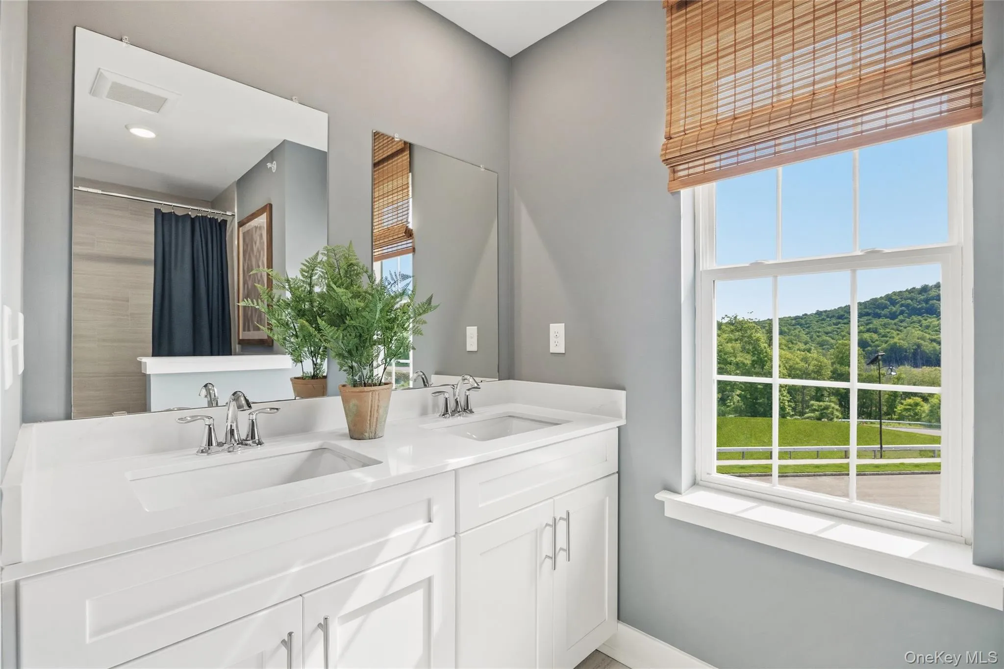 Bright bathroom featuring a double vanity with white cabinetry and light countertops. Bright bathroom featuring a double vanity with white cabinetry and light countertops.