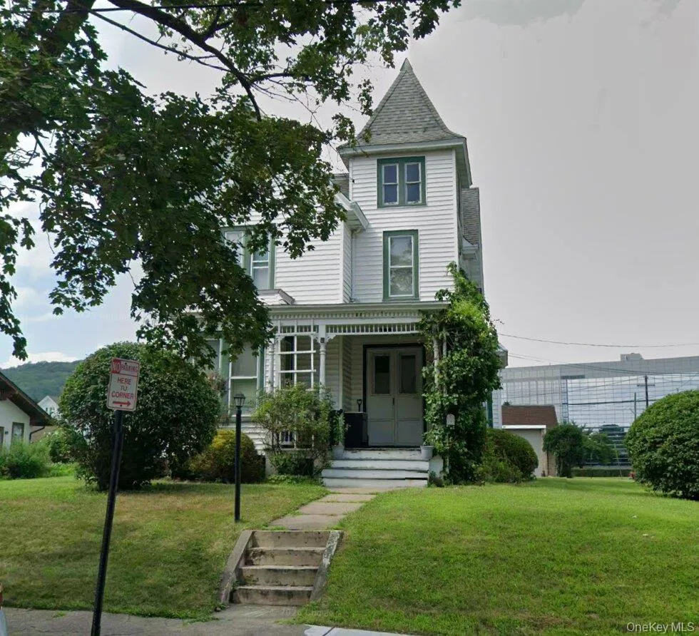 Victorian-style residence featuring a prominent turret, white siding, and a covered front porch Victorian-style residence featuring a prominent turret, white siding, and a covered front porch