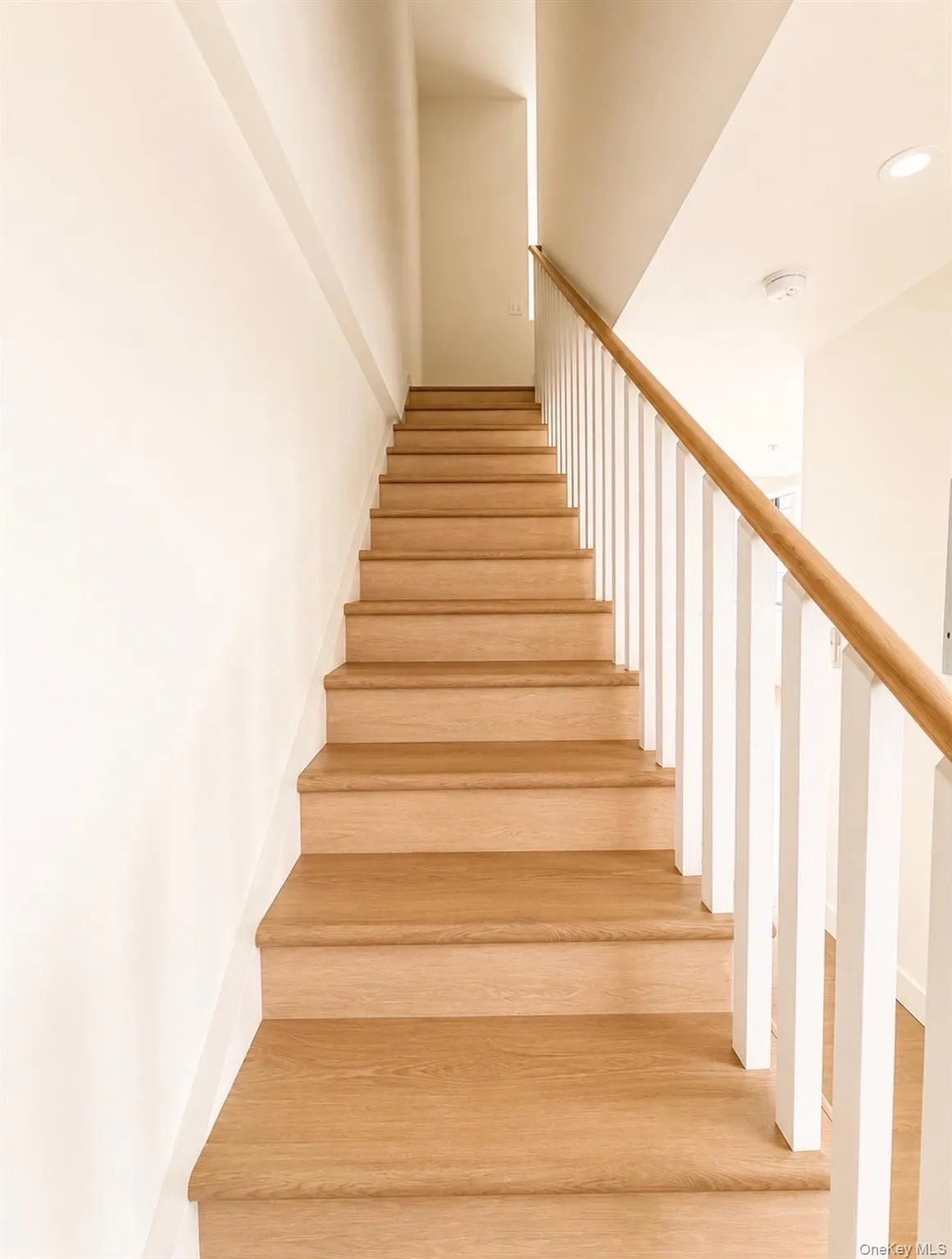Wood-finish staircase with a light wood handrail and white balusters Wood-finish staircase with a light wood handrail and white balusters