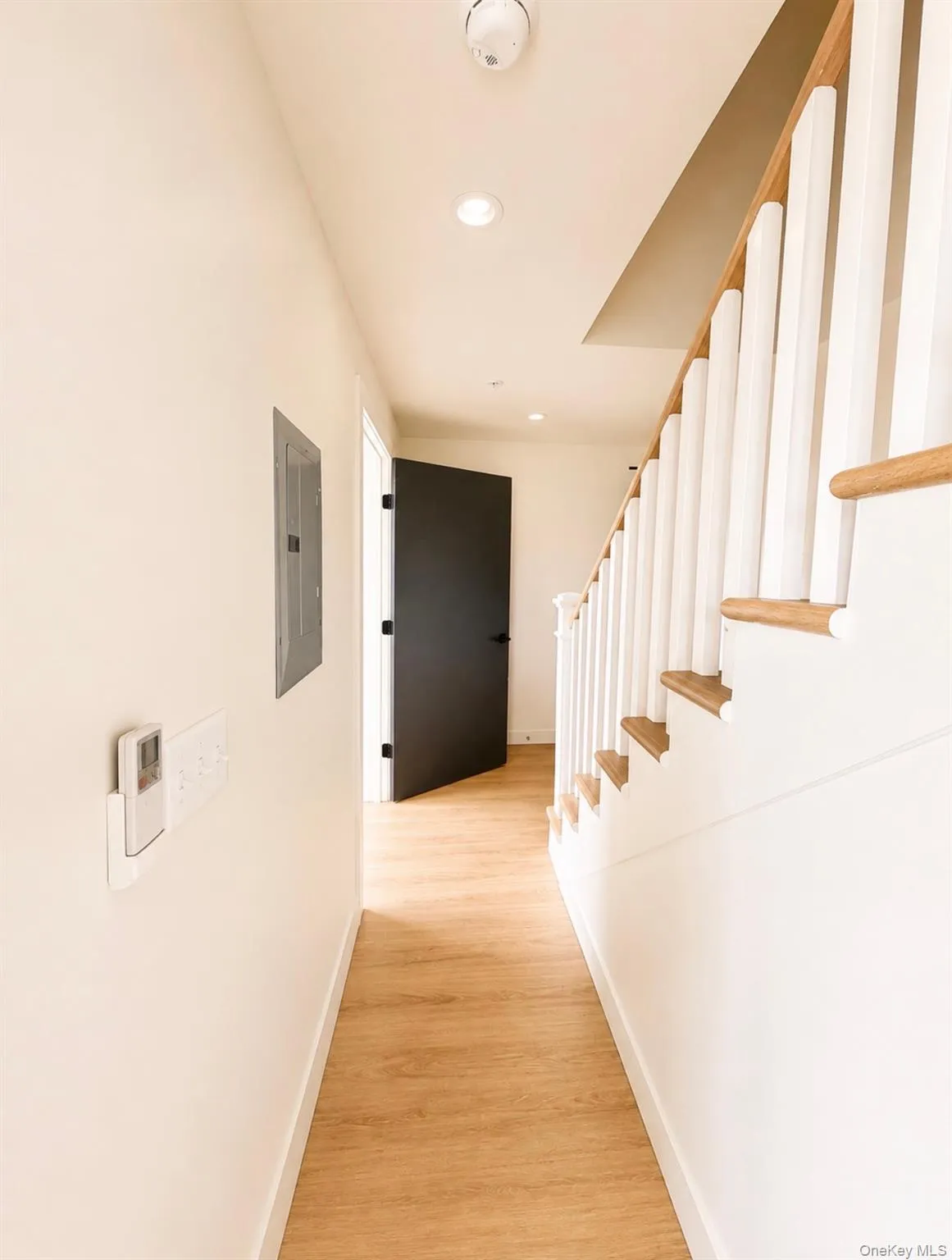 Wood-finish flooring, recessed lighting, and a white baluster staircase with wood handrails Wood-finish flooring, recessed lighting, and a white baluster staircase with wood handrails