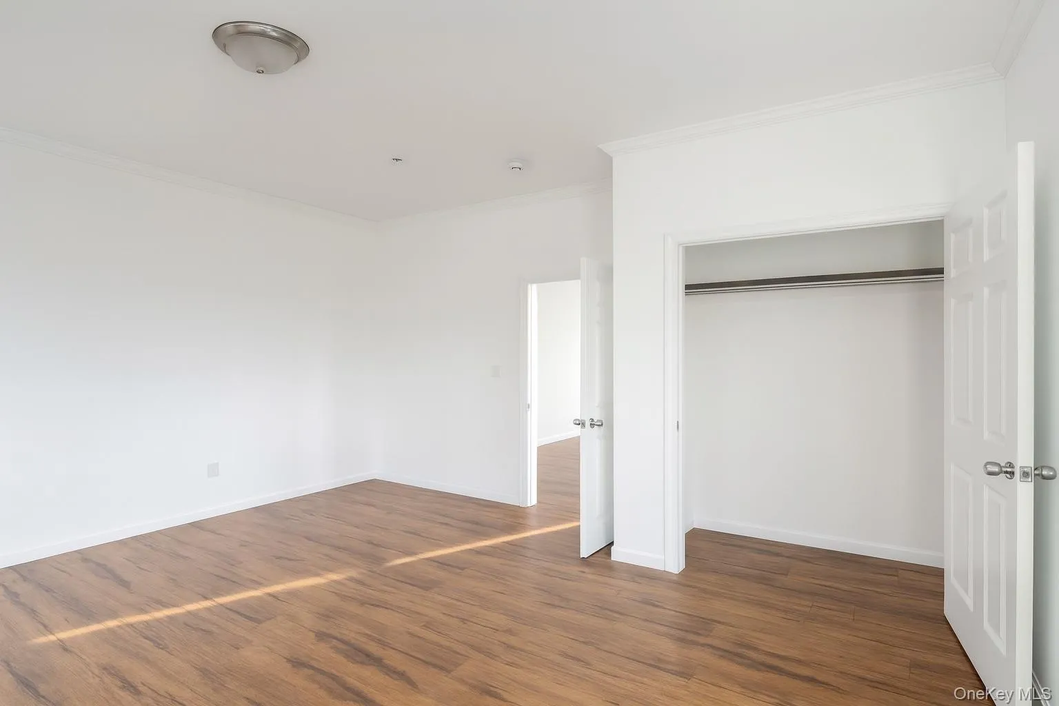 Unfurnished bedroom with dark wood-style floors, crown molding, and a closet Unfurnished bedroom with dark wood-style floors, crown molding, and a closet