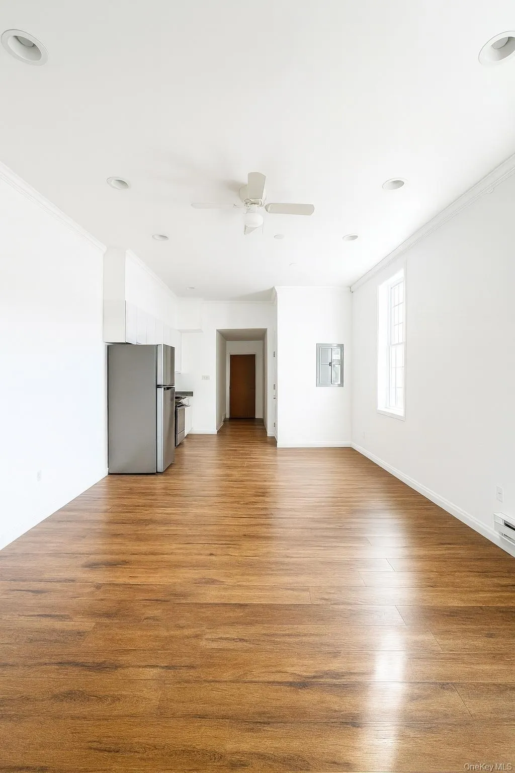 Unfurnished living room with crown molding, light wood-style flooring, a ceiling fan, and a baseboard heating unit Unfurnished living room with crown molding, light wood-style flooring, a ceiling fan, and a baseboard heating unit