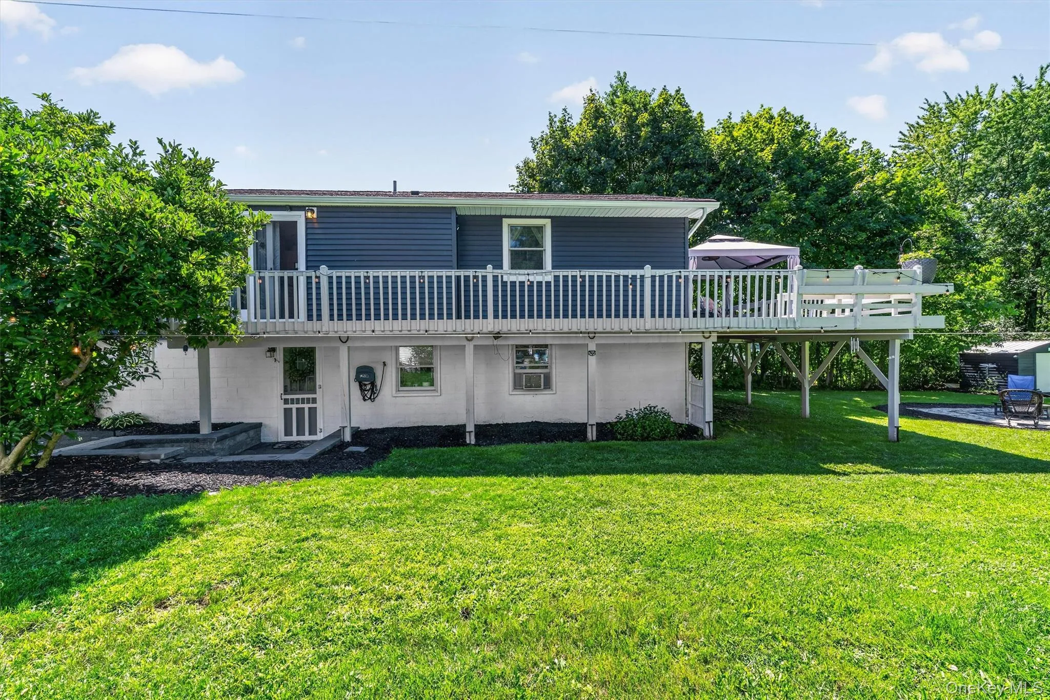 The right side of the property showing the kitchen sliders leading out to the wrap around deck and side entrance to lower level The right side of the property showing the kitchen sliders leading out to the wrap around deck and side entrance to lower level