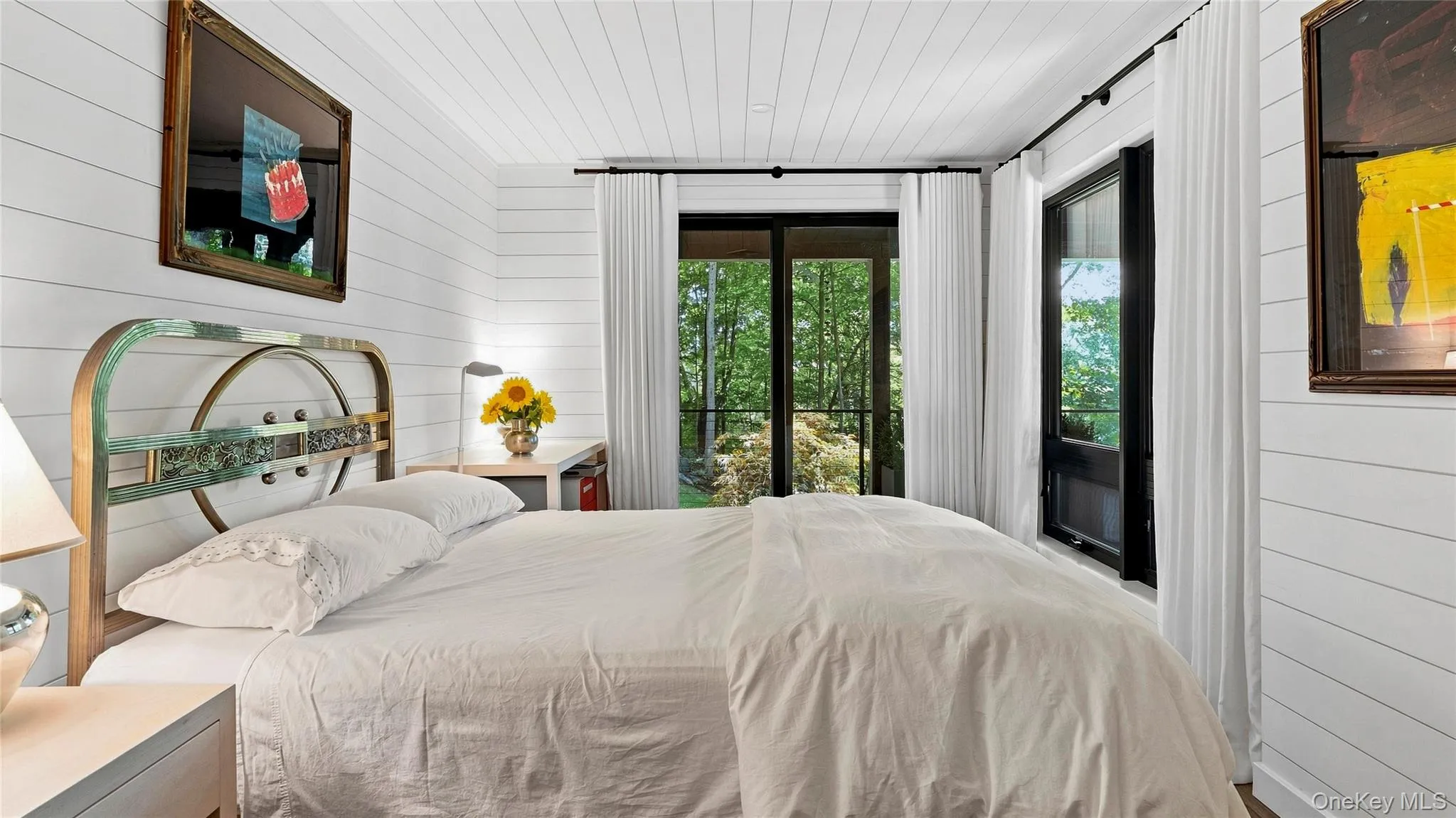 Comfortable guest bedroom with multiple exposures and doors opening to the wooded setting. Comfortable guest bedroom with multiple exposures and doors opening to the wooded setting.