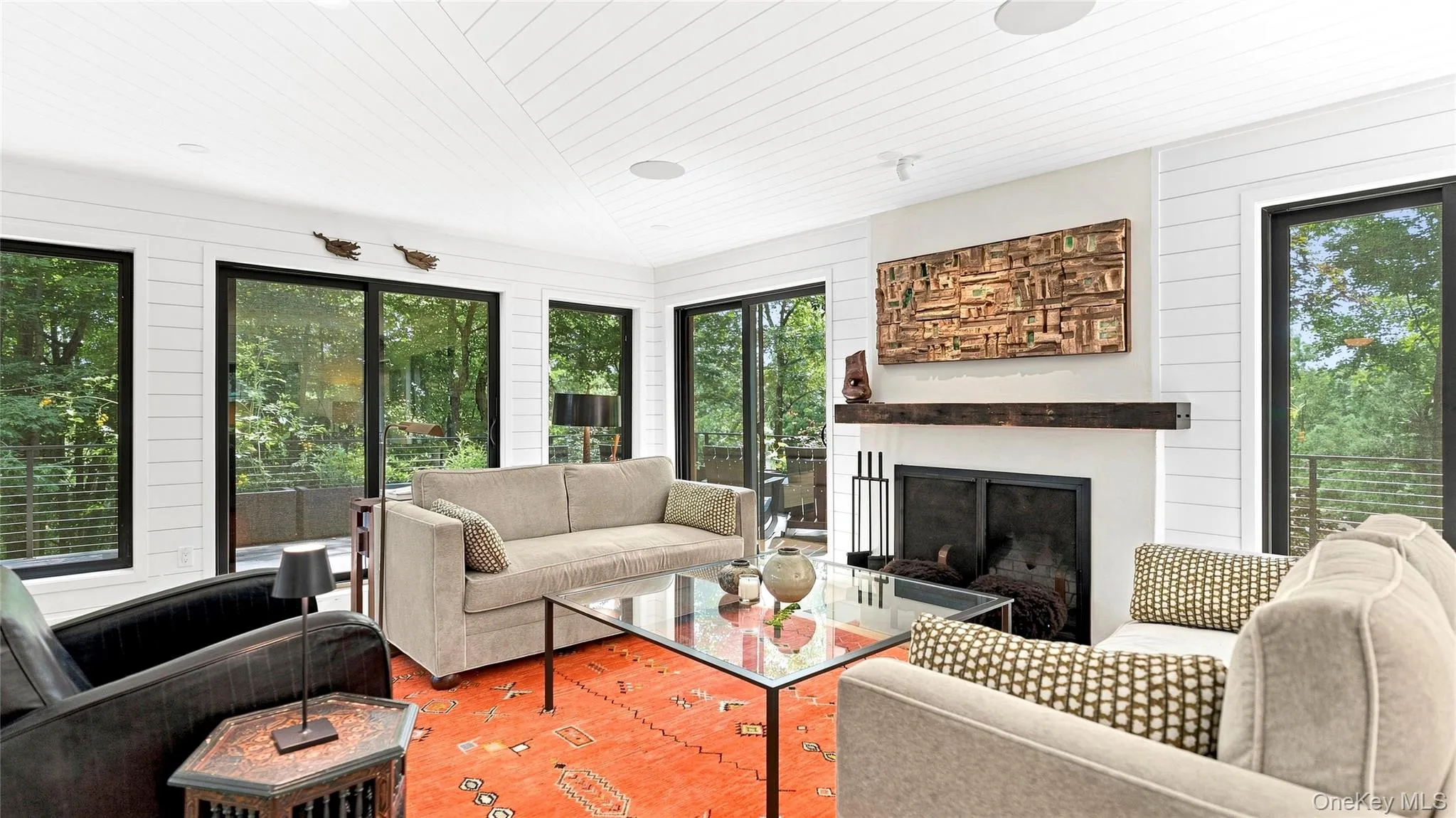 Walls of glass frame the setting, while the wood-burning fireplace anchors the bright, inviting living room. Walls of glass frame the setting, while the wood-burning fireplace anchors the bright, inviting living room.