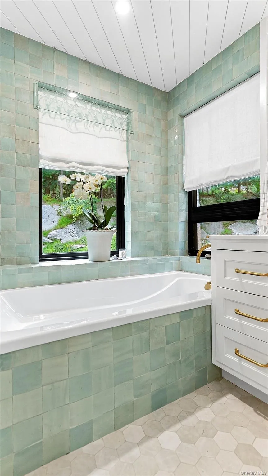 Soaking tub set beneath a window with peaceful woodland views—a spa-like escape within the primary suite. Soaking tub set beneath a window with peaceful woodland views—a spa-like escape within the primary suite.