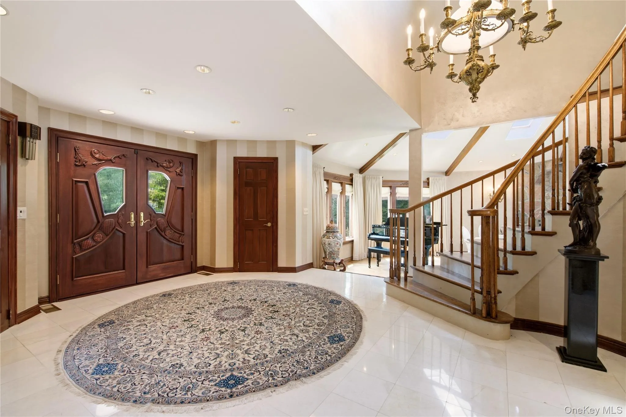 Grand entry with custom carved double doors, marble flooring, a curved staircase with wood balusters. Grand entry with custom carved double doors, marble flooring, a curved staircase with wood balusters.