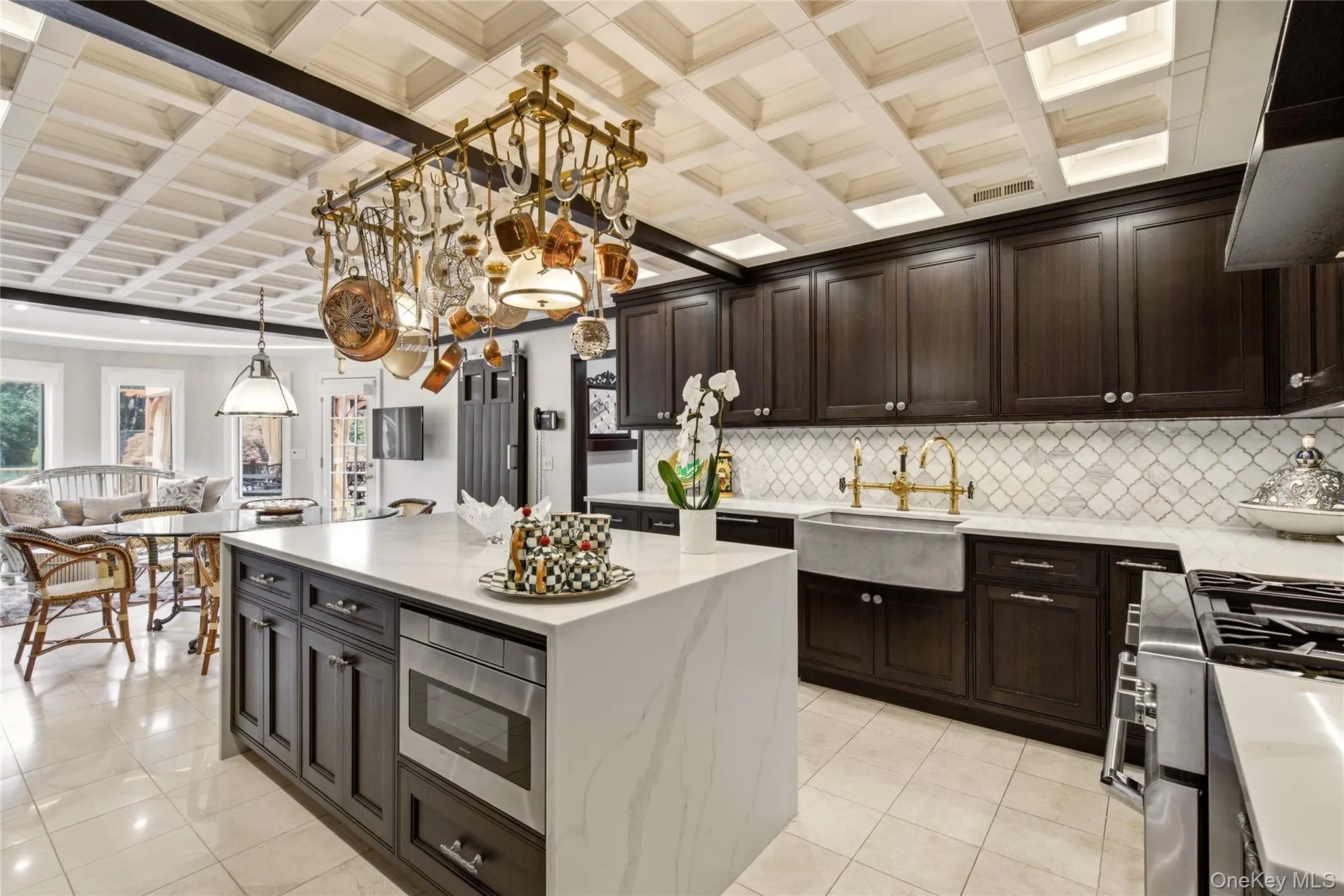 Coffered ceiling with recessed lighting, Farmhouse stone sink with brass-finish faucet, and a center island with integrated microwave Coffered ceiling with recessed lighting, Farmhouse stone sink with brass-finish faucet, and a center island with integrated microwave