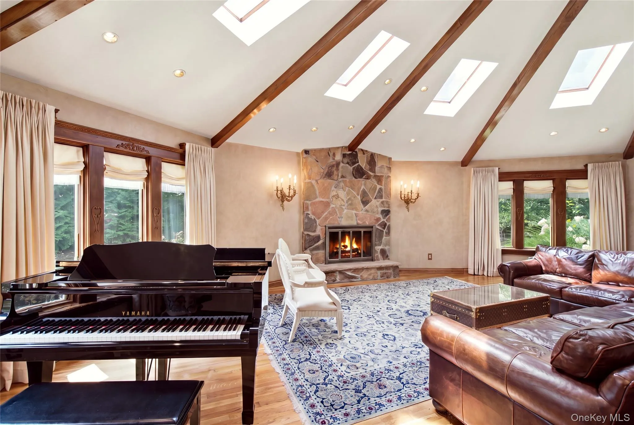 Vaulted ceiling with exposed wood beams, multiple skylights, stone-clad fireplace, and hardwood flooring Vaulted ceiling with exposed wood beams, multiple skylights, stone-clad fireplace, and hardwood flooring