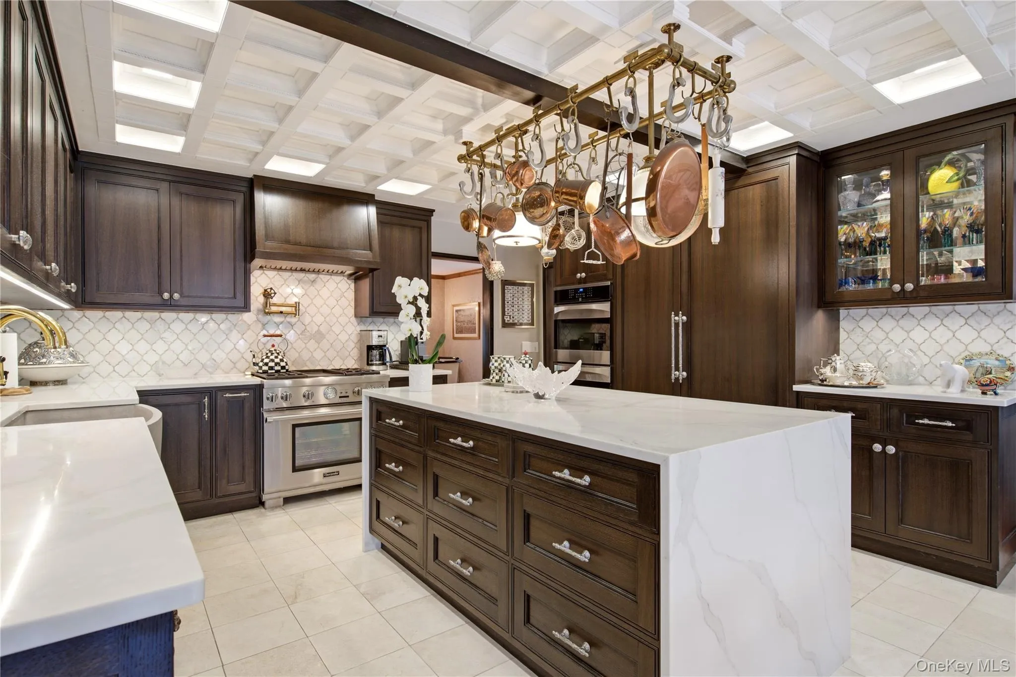 Kitchen featuring a coffered ceiling, black oak cabinetry, quartz countertops, a large center island, and stainless steel appliances Kitchen featuring a coffered ceiling, black oak cabinetry, quartz countertops, a large center island, and stainless steel appliances