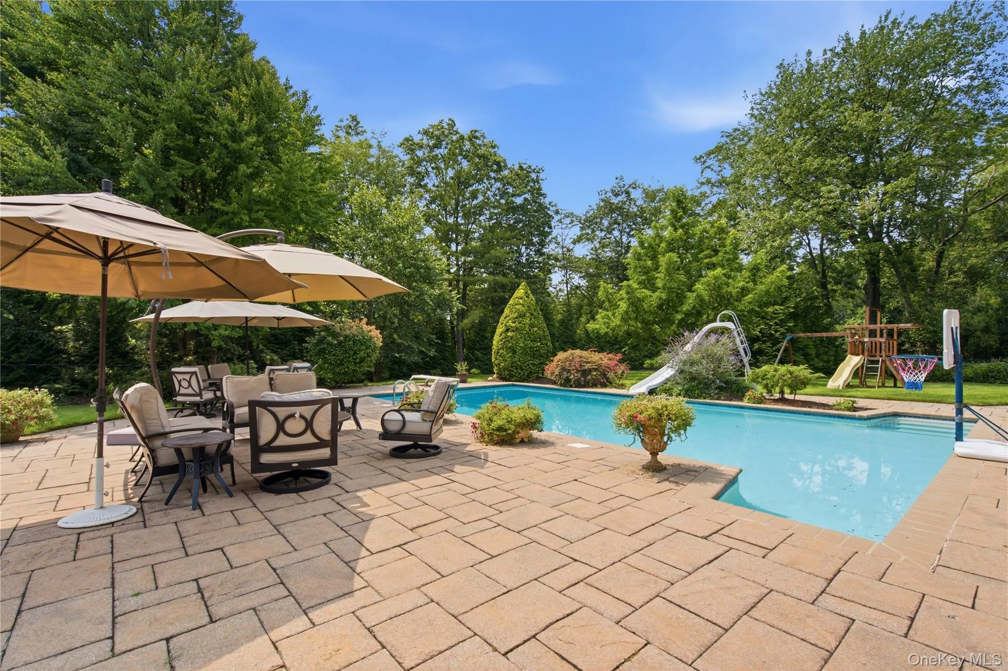 Expansive paver patio surrounding a rectangular swimming pool Expansive paver patio surrounding a rectangular swimming pool