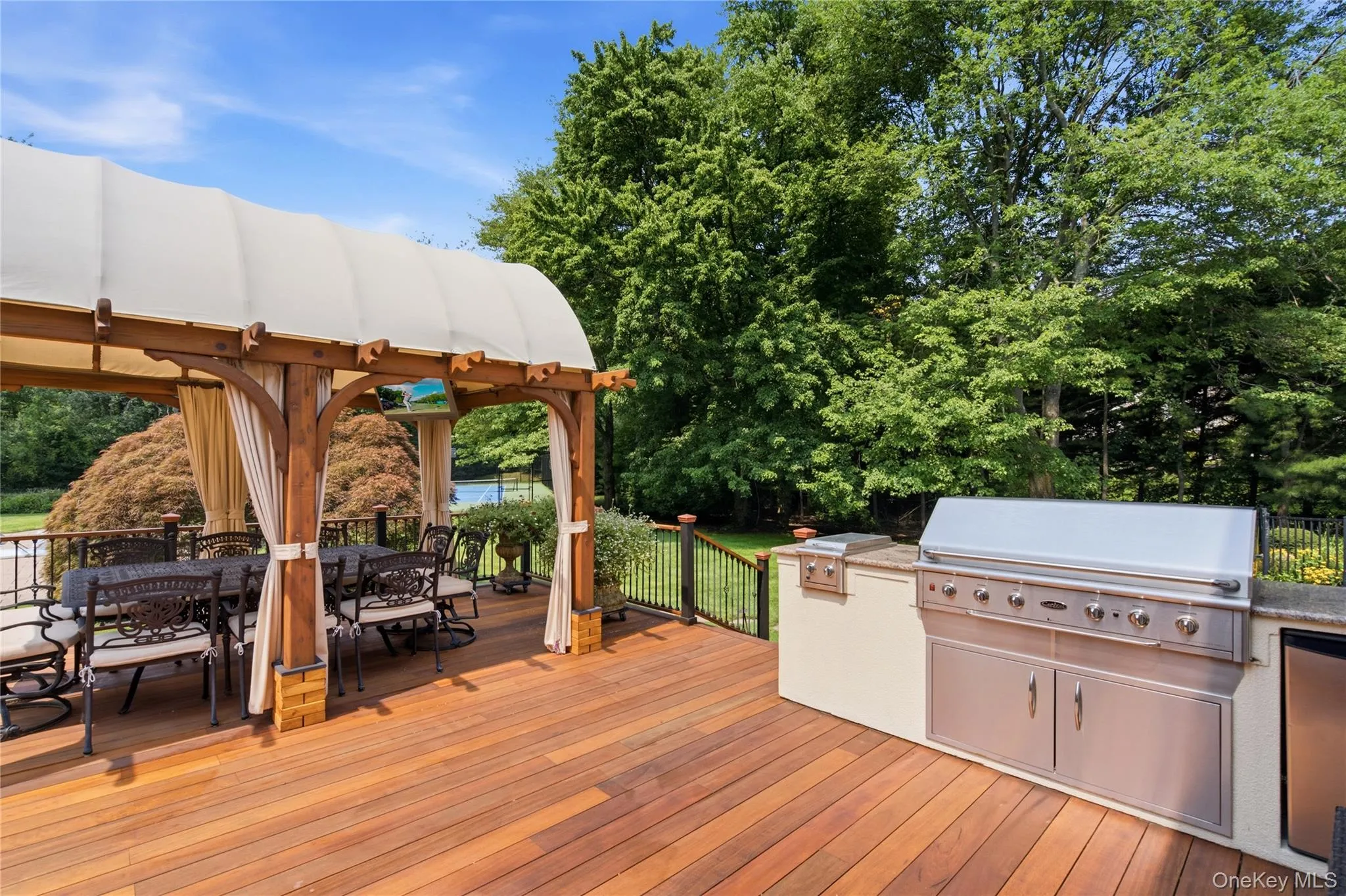 Expansive wood-finish deck featuring a covered pergola, built-in outdoor kitchen with stainless steel appliances. Expansive wood-finish deck featuring a covered pergola, built-in outdoor kitchen with stainless steel appliances.
