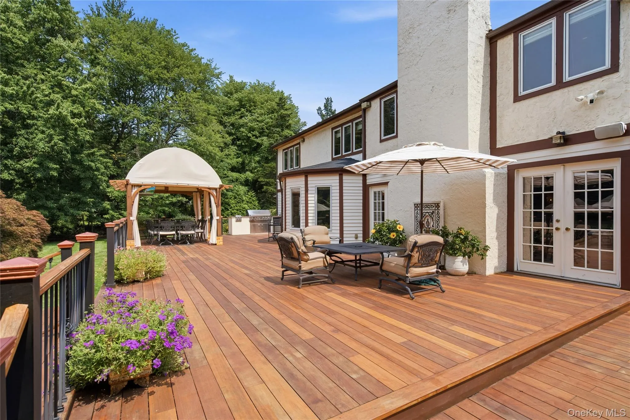 Expansive mahogany-finish deck with pergola and built-in outdoor kitchen, and French doors providing direct access to the interior Expansive mahogany-finish deck with pergola and built-in outdoor kitchen, and French doors providing direct access to the interior
