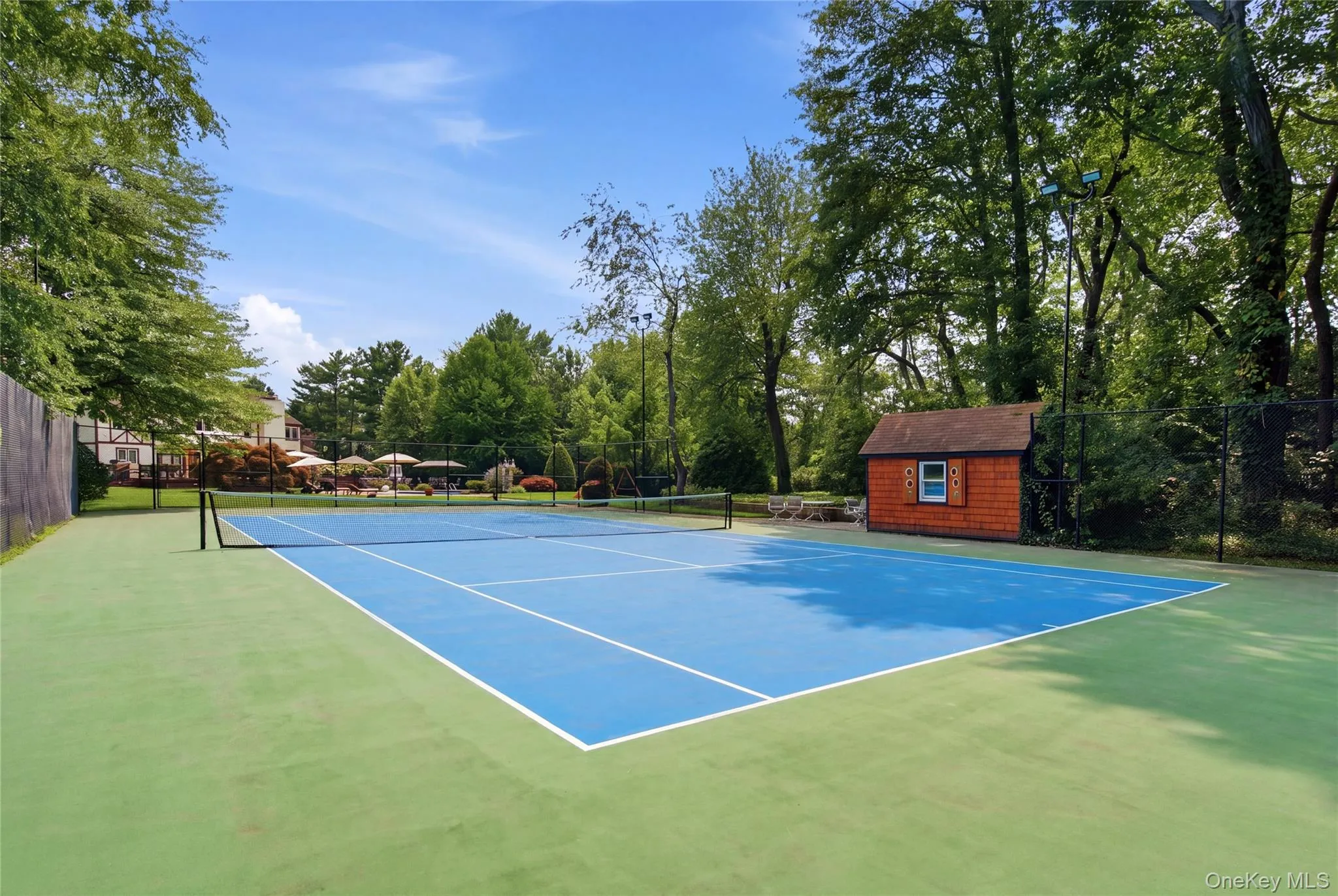 Tennis court featuring a blue playing surface, and perimeter fencing Tennis court featuring a blue playing surface, and perimeter fencing
