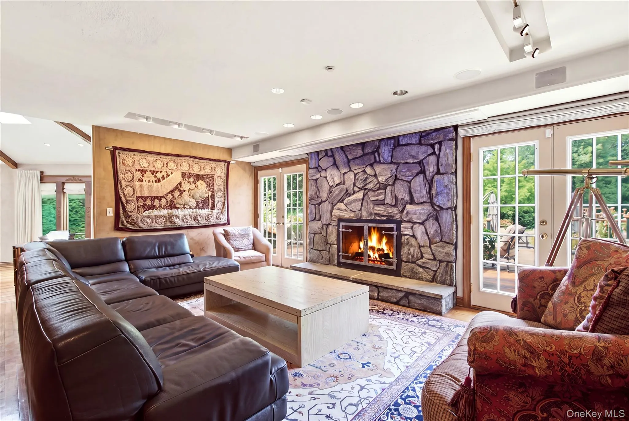 Stone-clad fireplace, wood-finish flooring, and French doors Stone-clad fireplace, wood-finish flooring, and French doors
