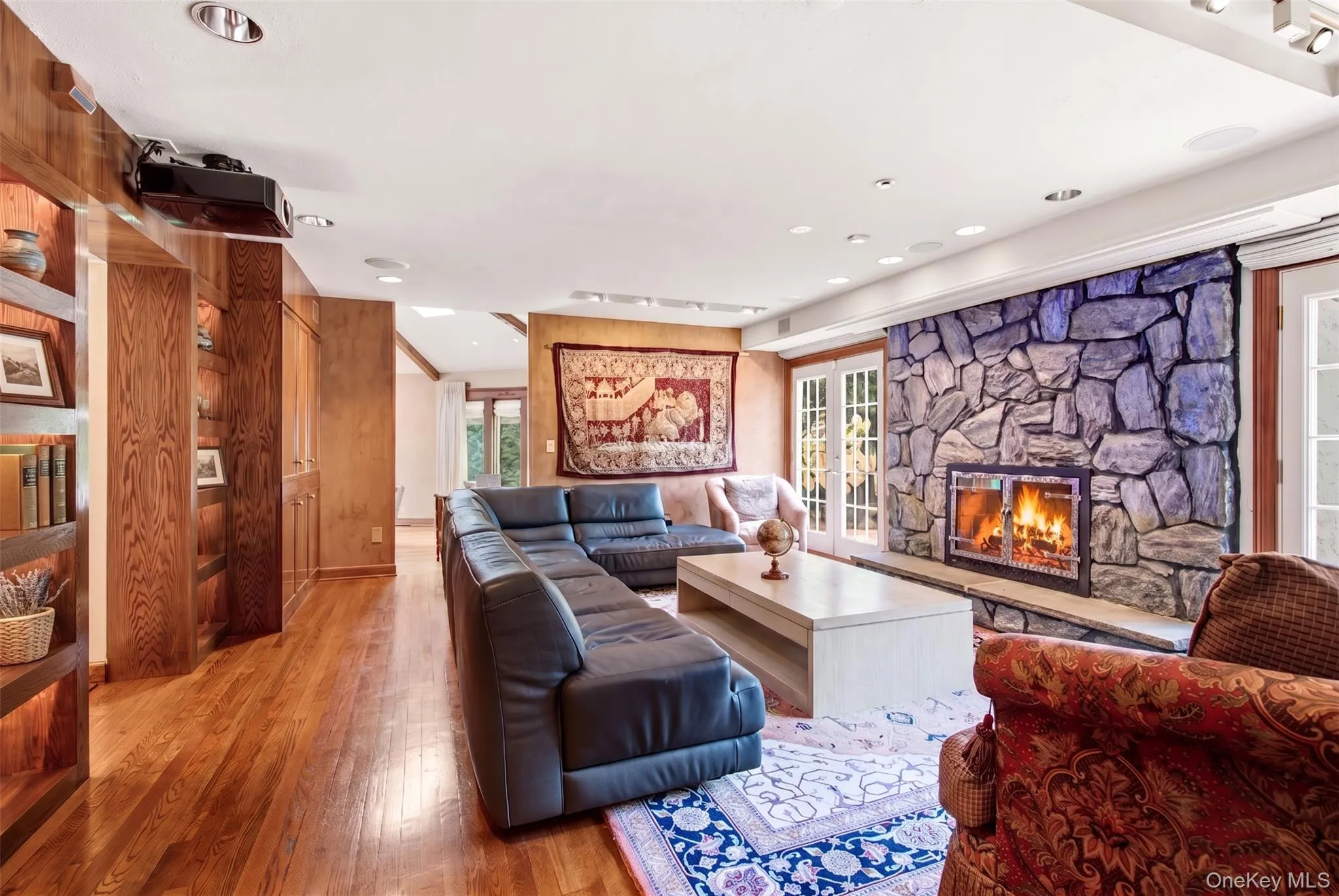 Stone fireplace with hearth, wood-finish flooring, built-in shelving, built-in cabinetry, recessed lighting Stone fireplace with hearth, wood-finish flooring, built-in shelving, built-in cabinetry, recessed lighting