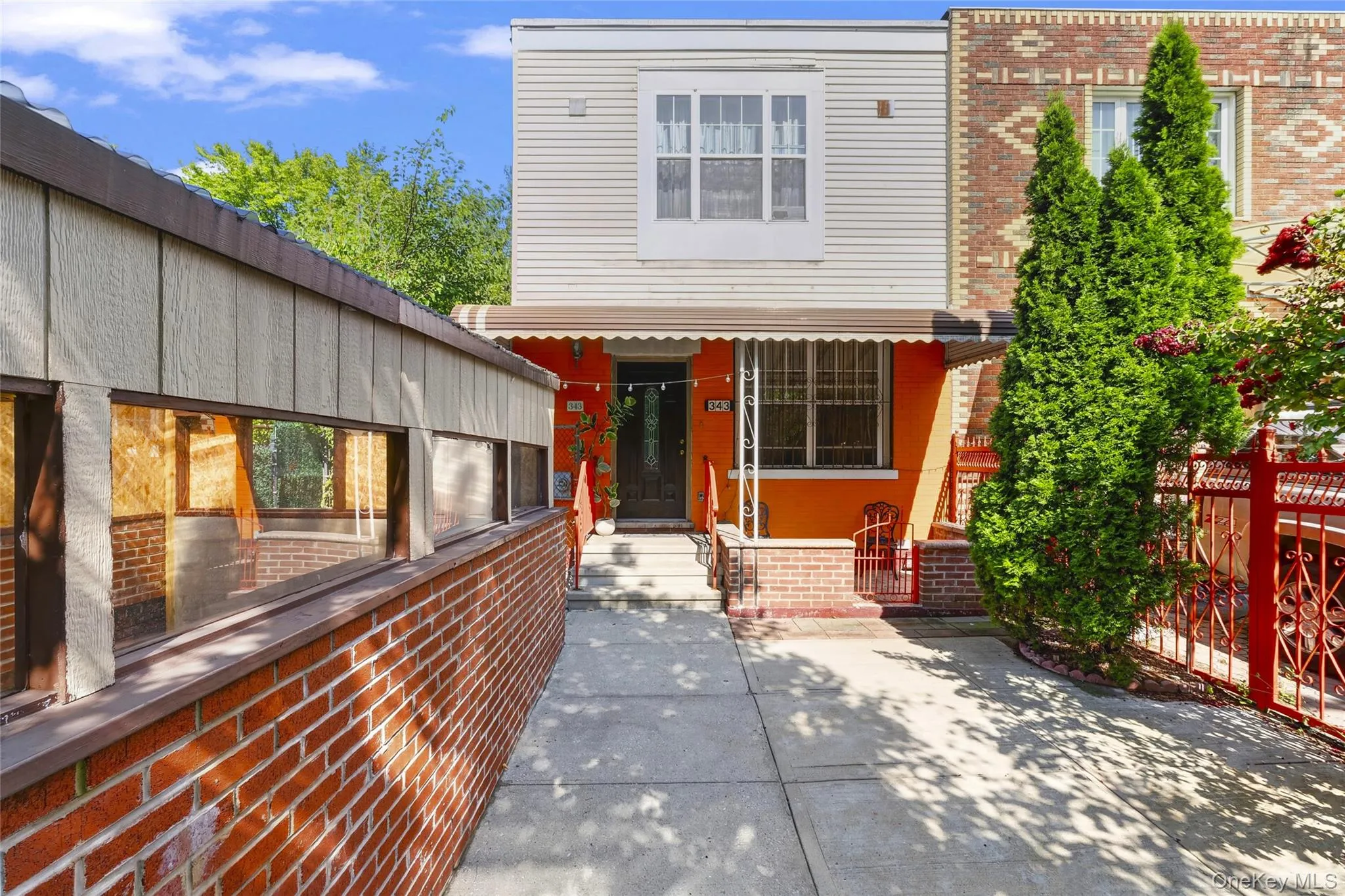 Front yard courtyard with paved walkway, covered entrance porch, and privacy fencing. Front yard courtyard with paved walkway, covered entrance porch, and privacy fencing.
