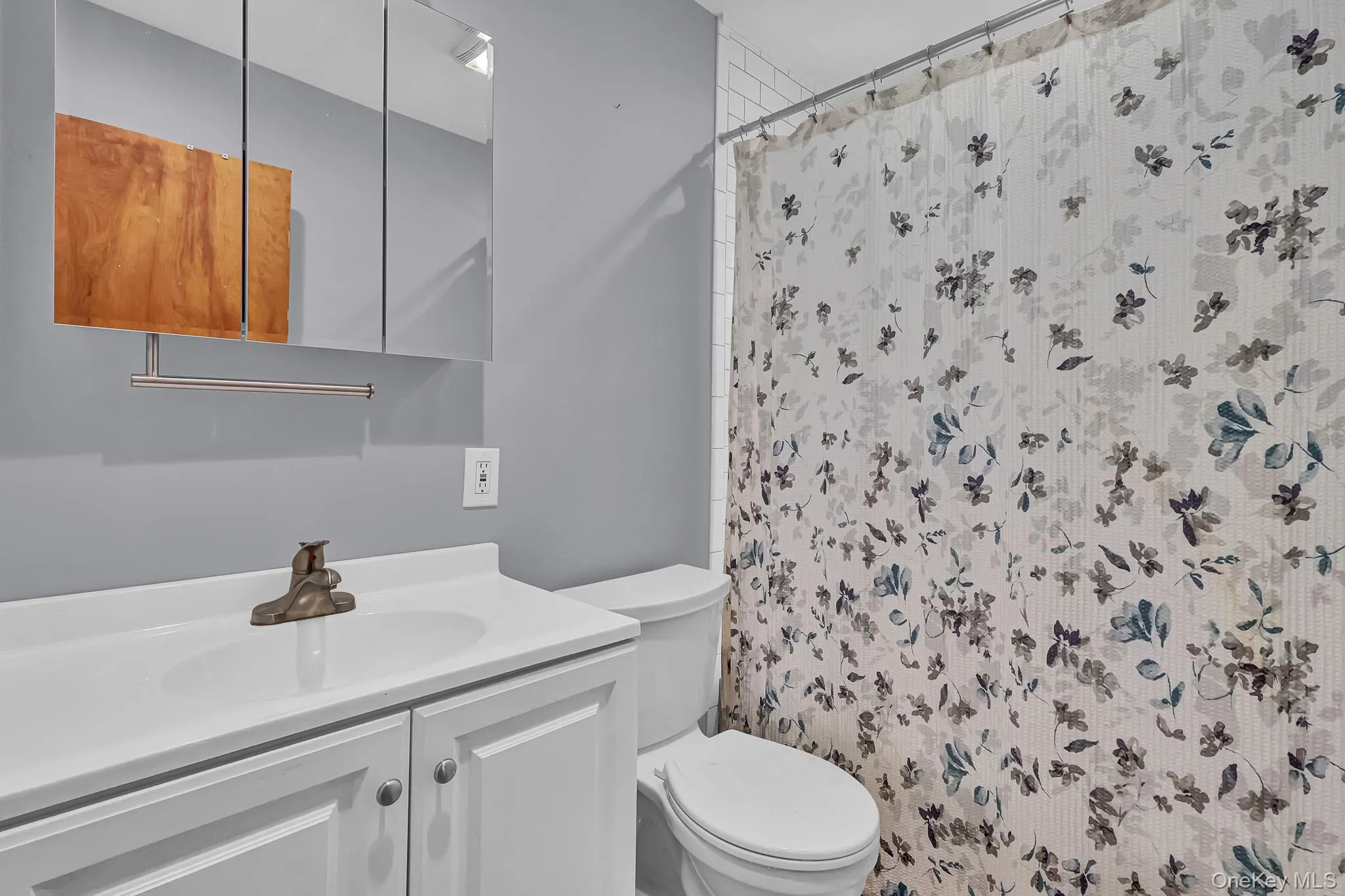 White vanity with integrated sink, tri-fold mirrored medicine cabinet, and white toilet White vanity with integrated sink, tri-fold mirrored medicine cabinet, and white toilet
