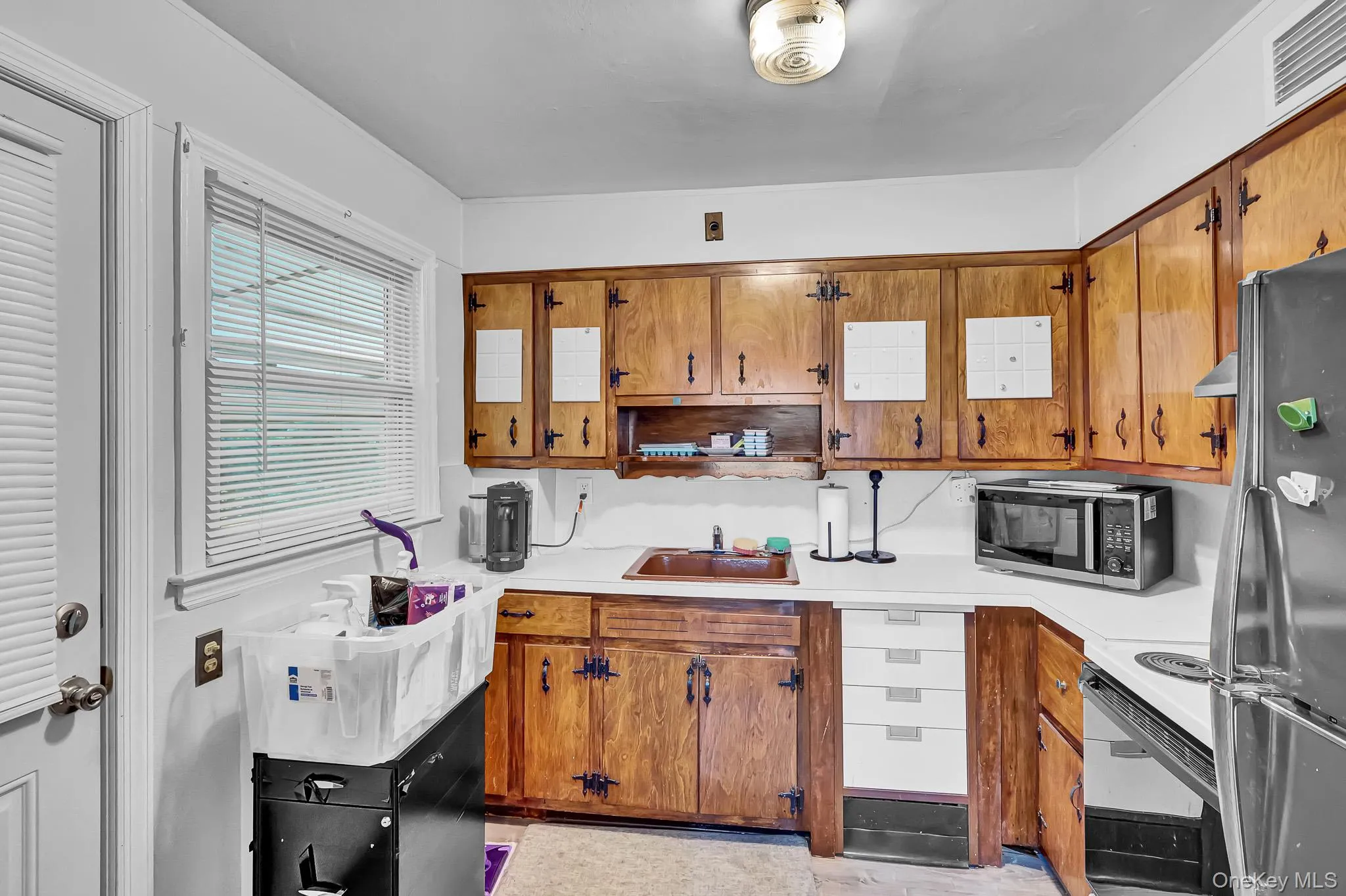 Kitchen featuring wood-finish cabinetry, white countertops, a single-basin sink, and a built-in oven range Kitchen featuring wood-finish cabinetry, white countertops, a single-basin sink, and a built-in oven range
