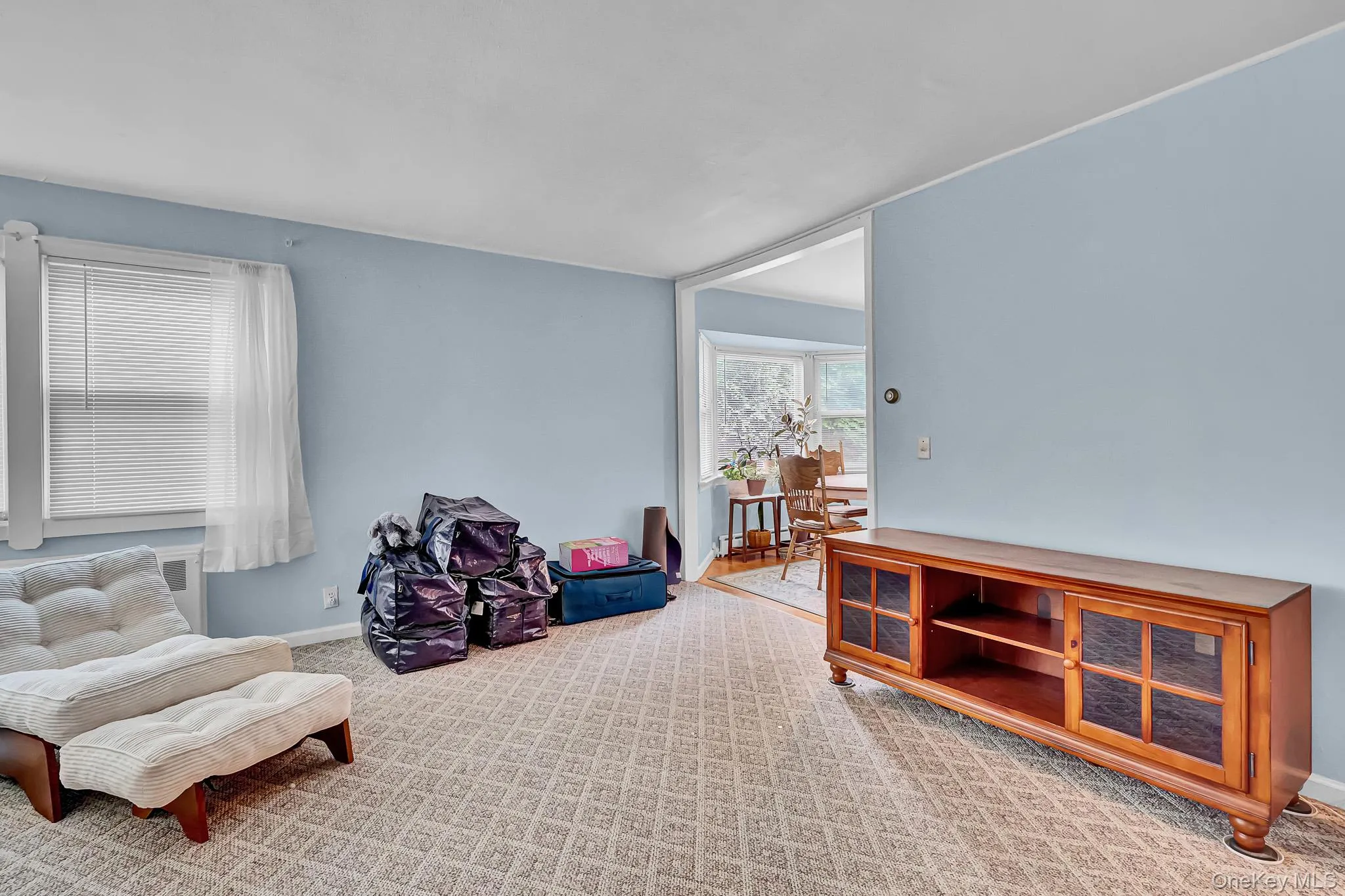 Wall-to-wall carpeting with a geometric pattern, neutral wall color, and a window with blinds Wall-to-wall carpeting with a geometric pattern, neutral wall color, and a window with blinds